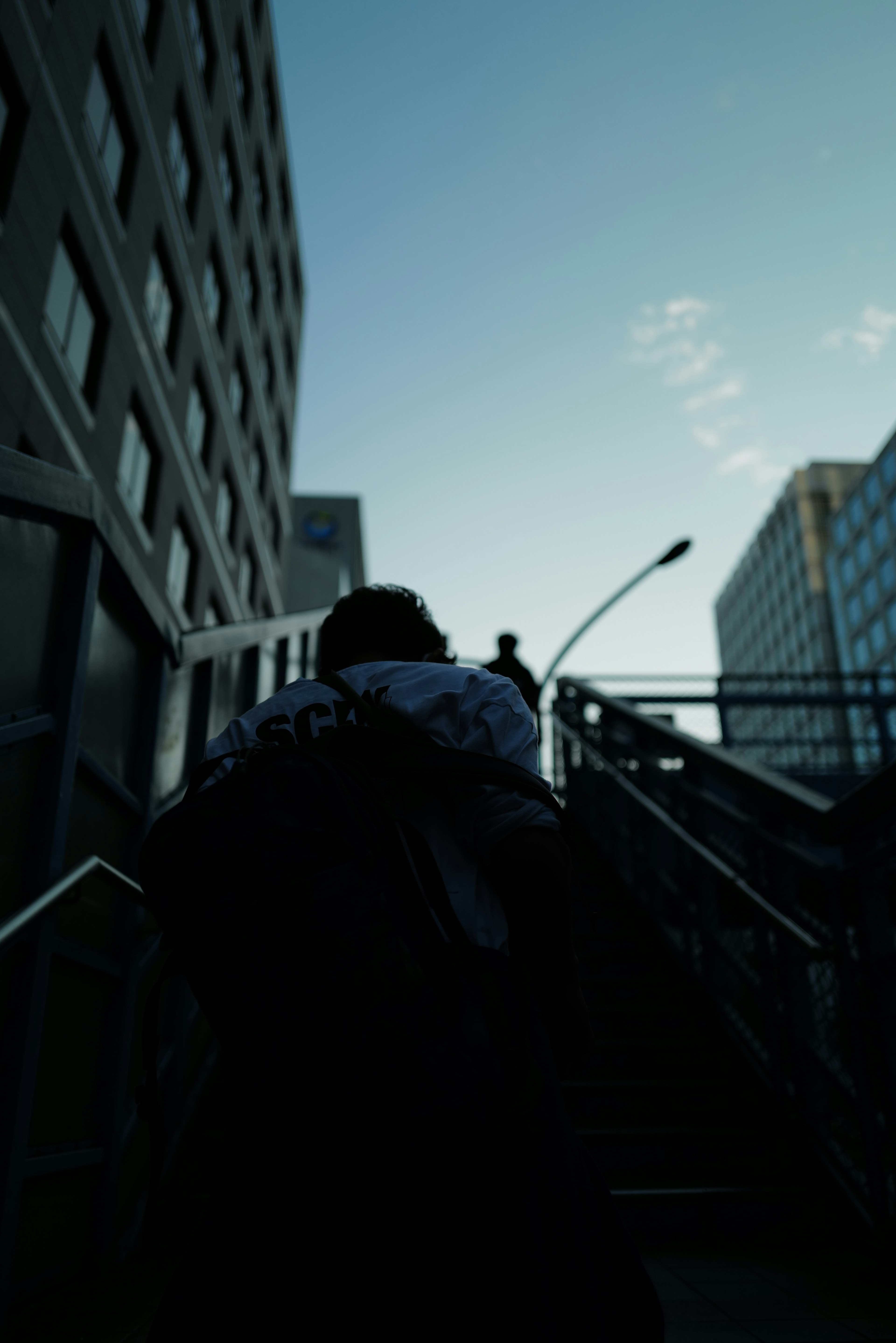 Silhouette of a person ascending stairs with city buildings in the background