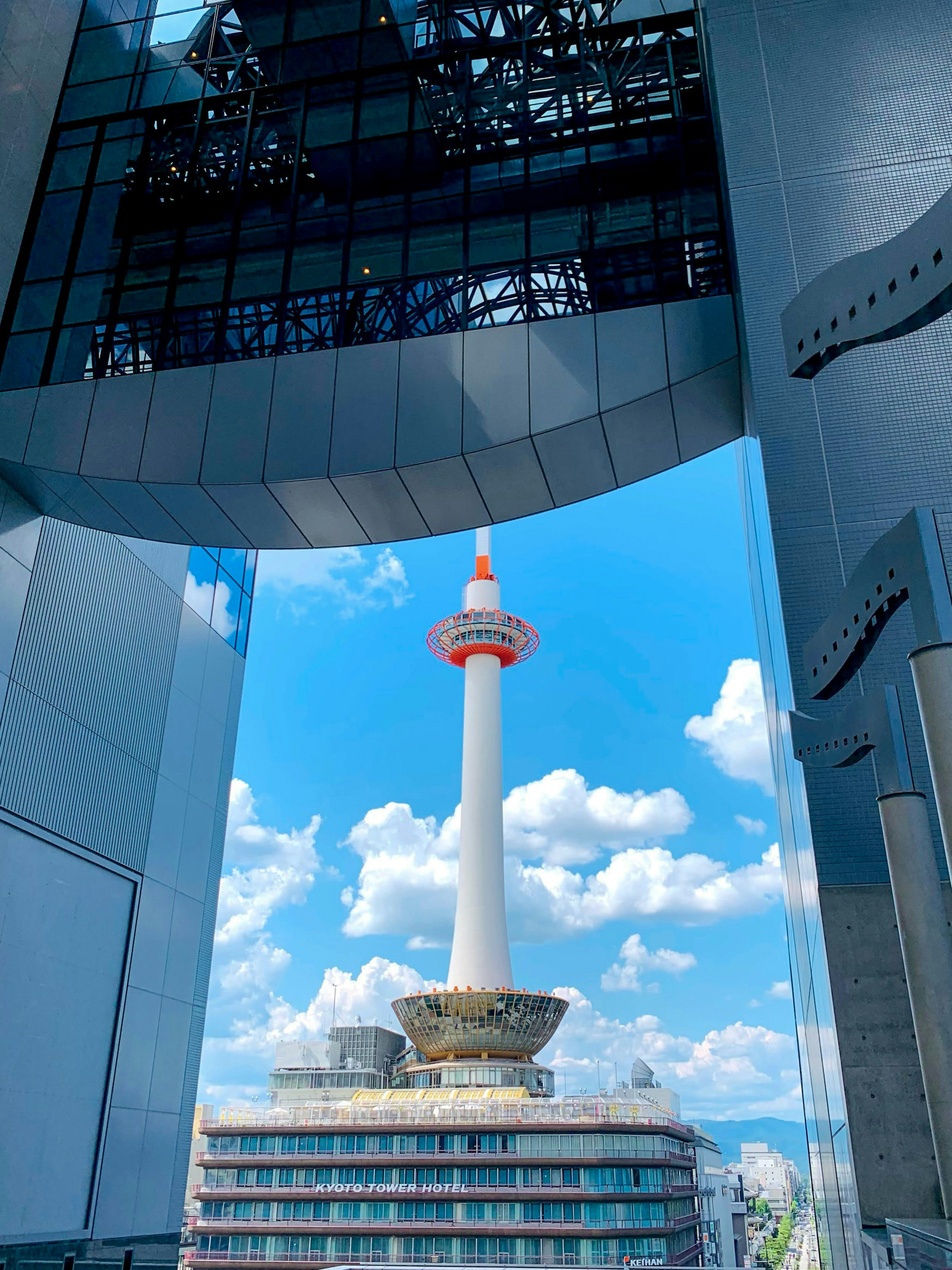 View of Kyoto Tower under the blue sky from a modern building