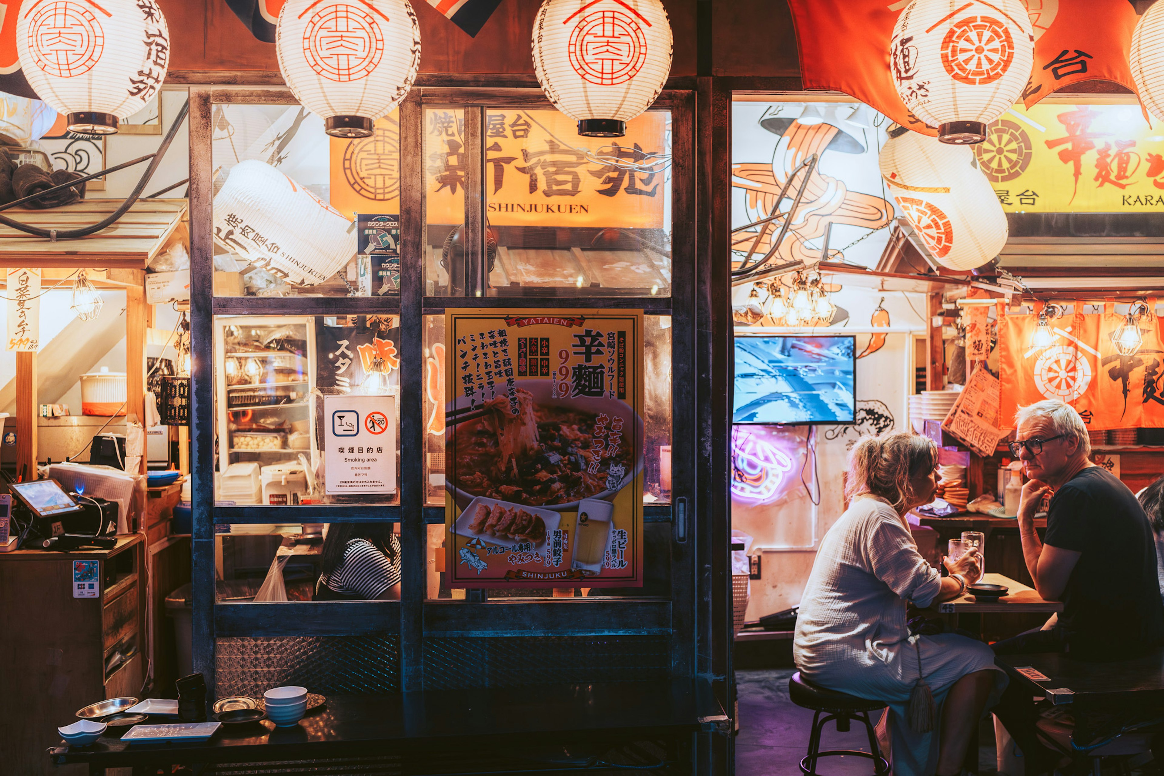 Couple enjoying a meal in front of a street food stall with lanterns and a warm ambiance