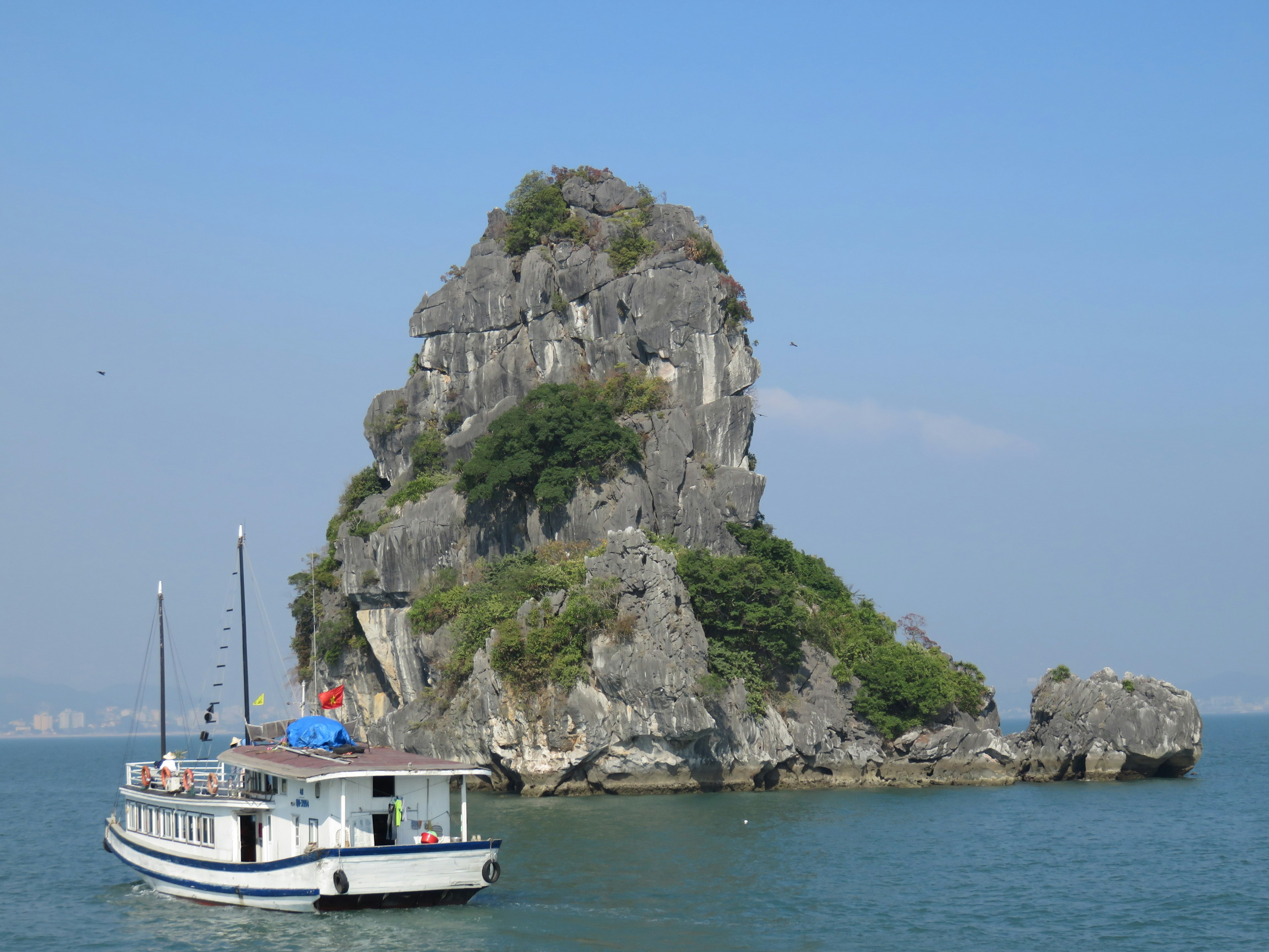 Eine kleine Insel mit Grün und einem Boot auf klarem blauen Wasser