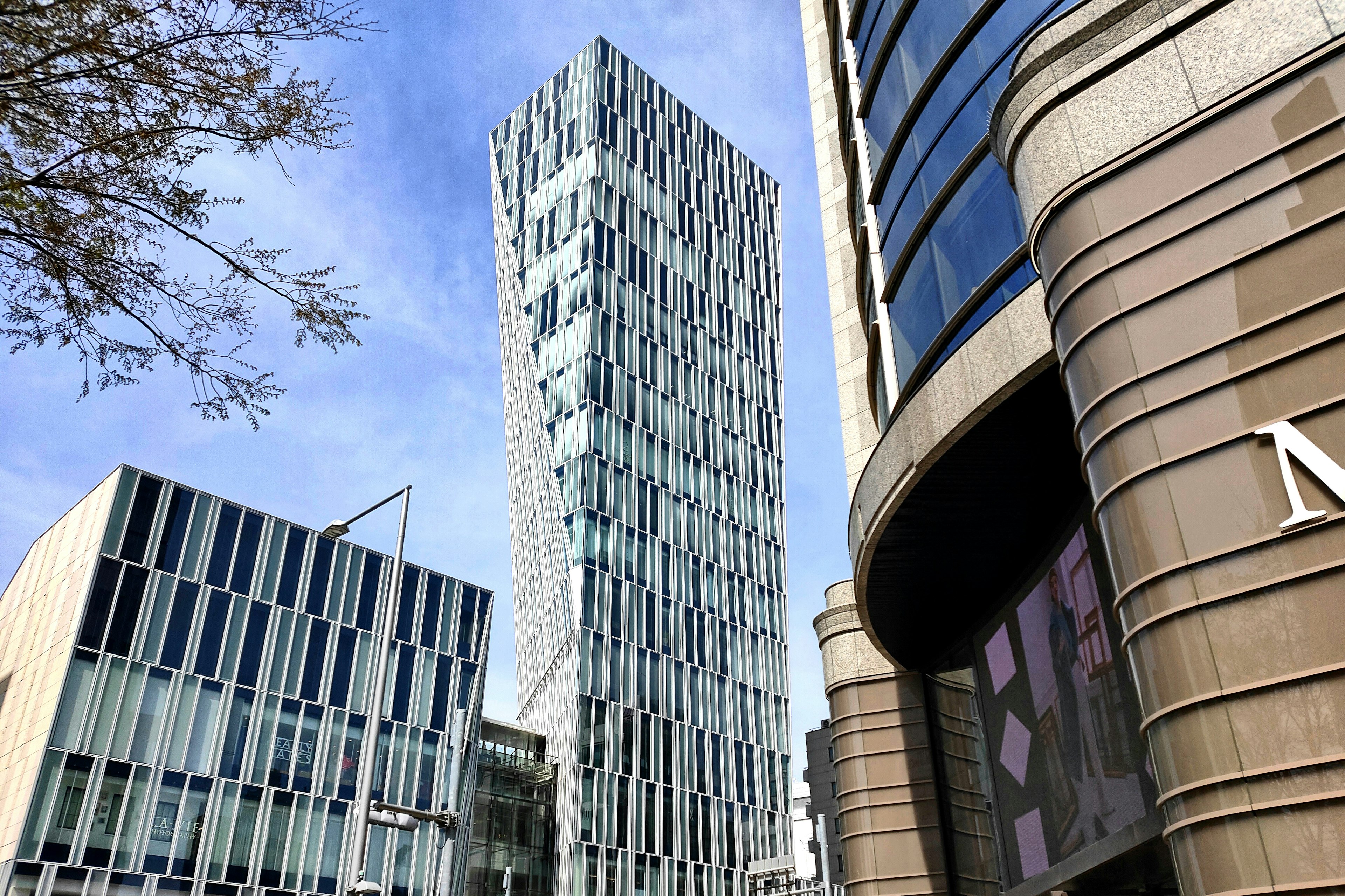 Modern skyscraper with unique glass facade alongside contemporary buildings