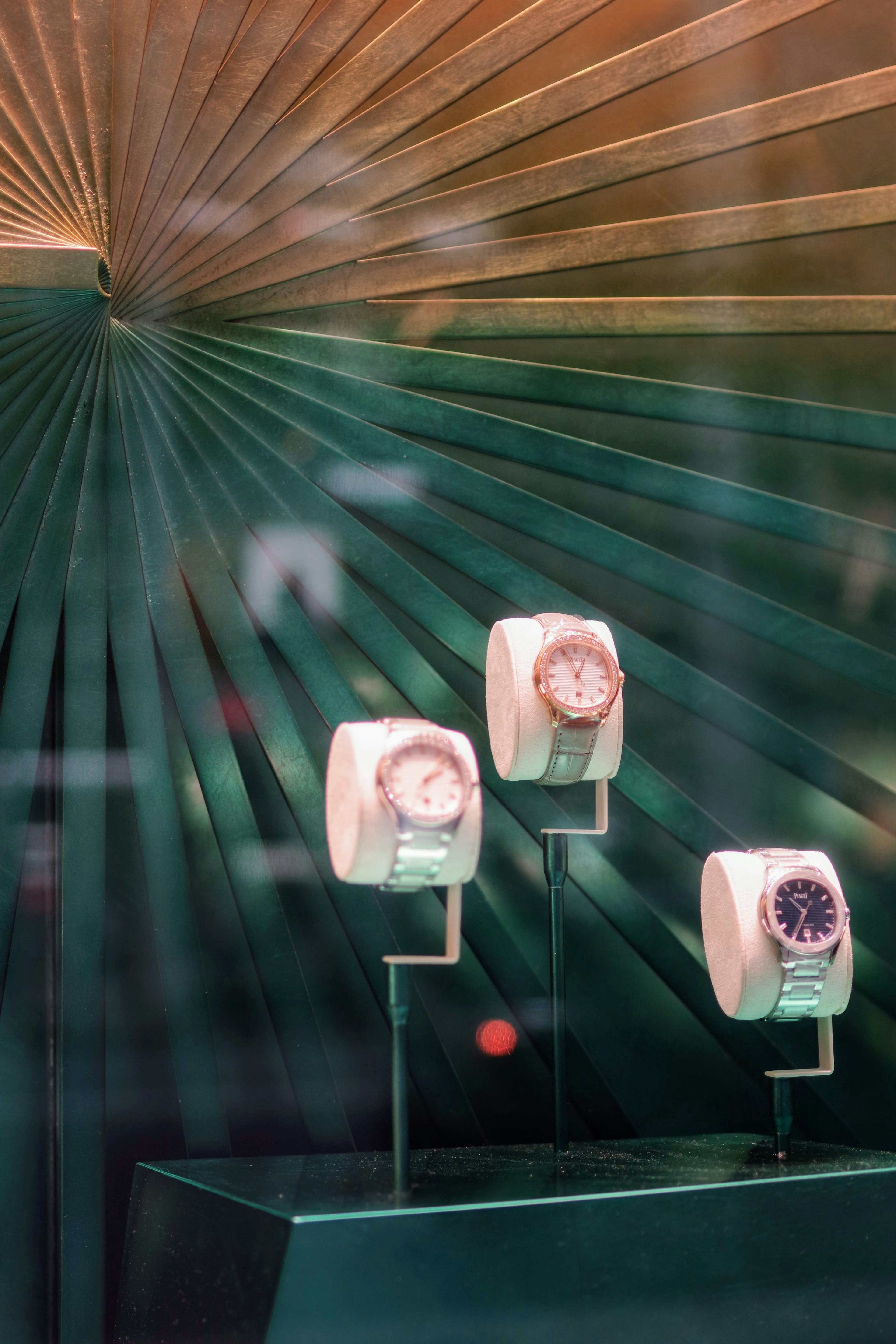 Display of watches in a shop window with a green background