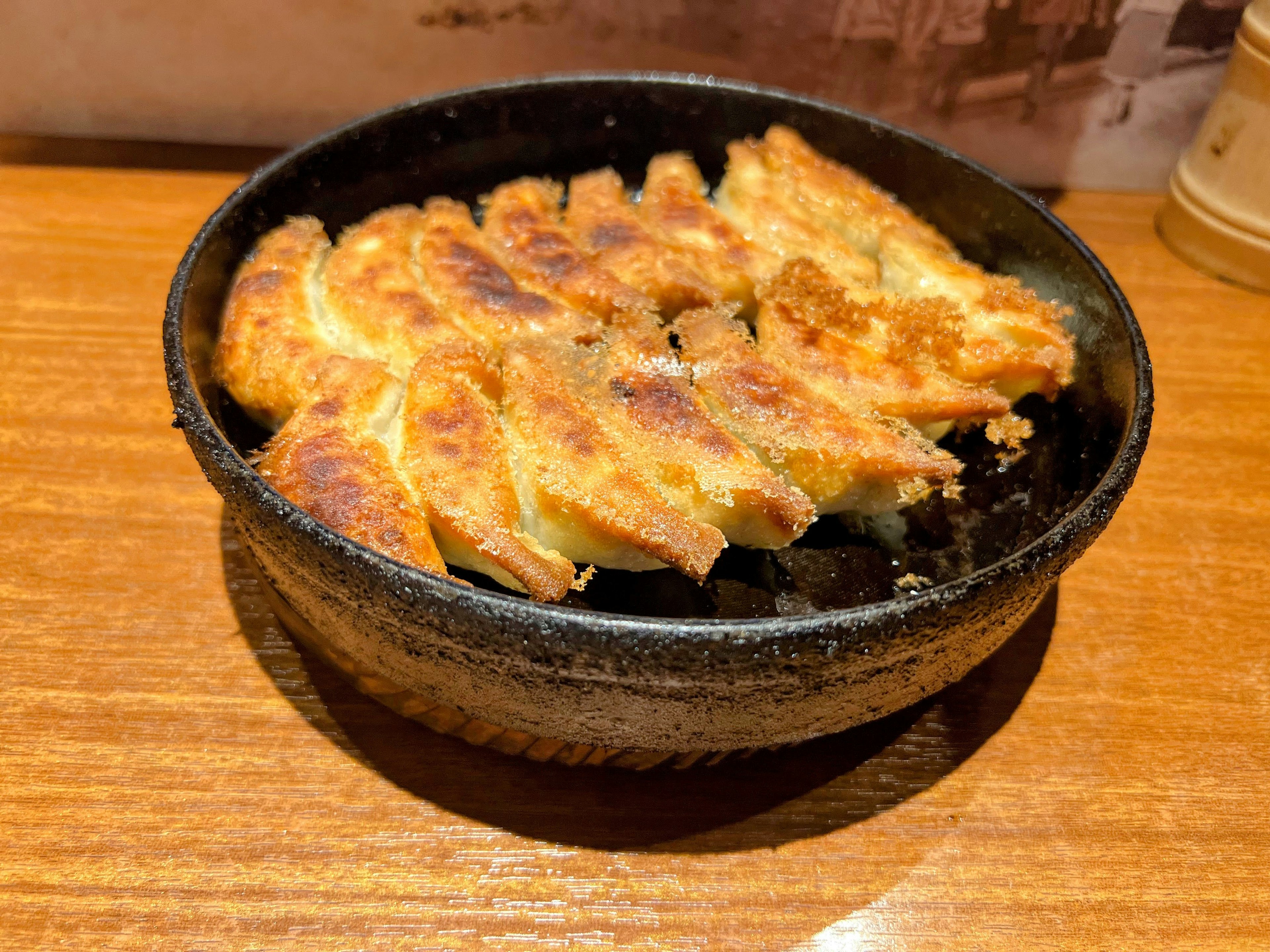 焦げ目のついた餃子が盛られた黒い皿