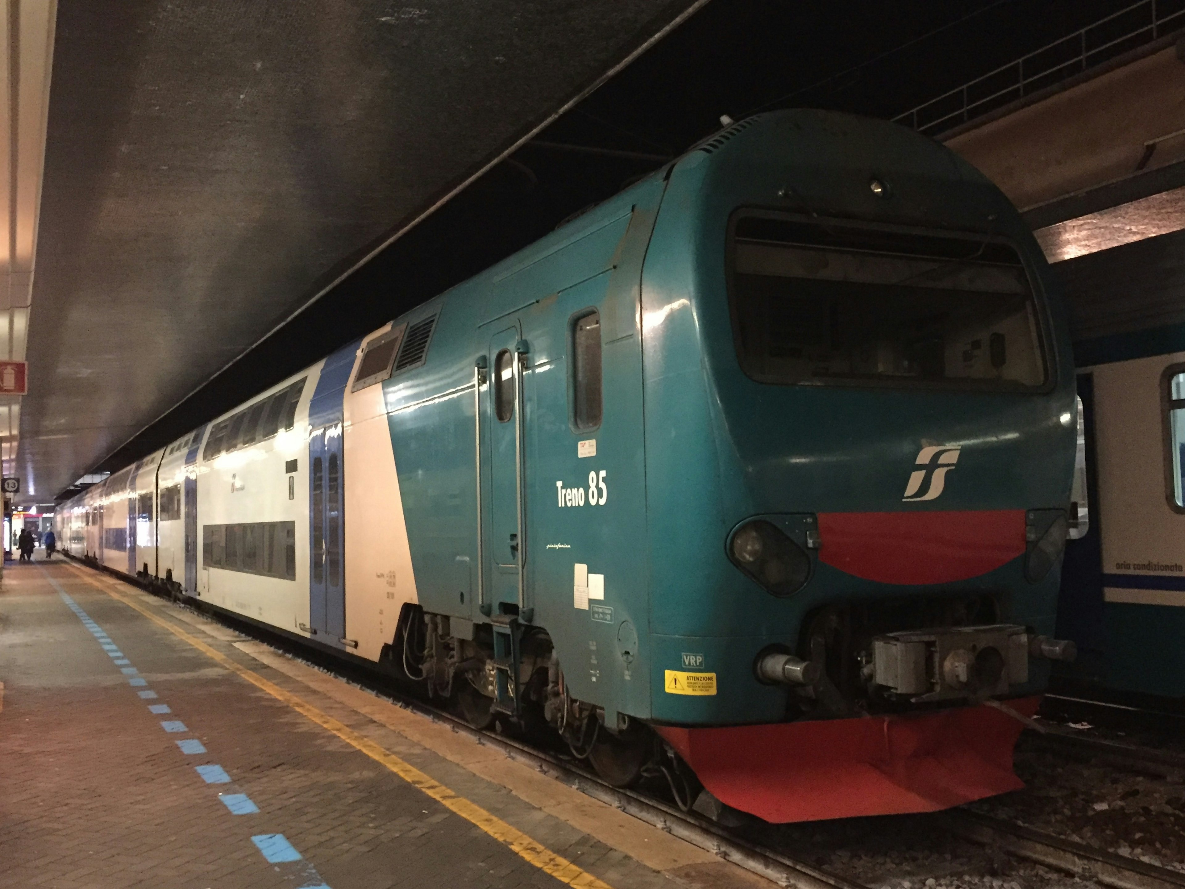 Blue and white Italian train parked at a station