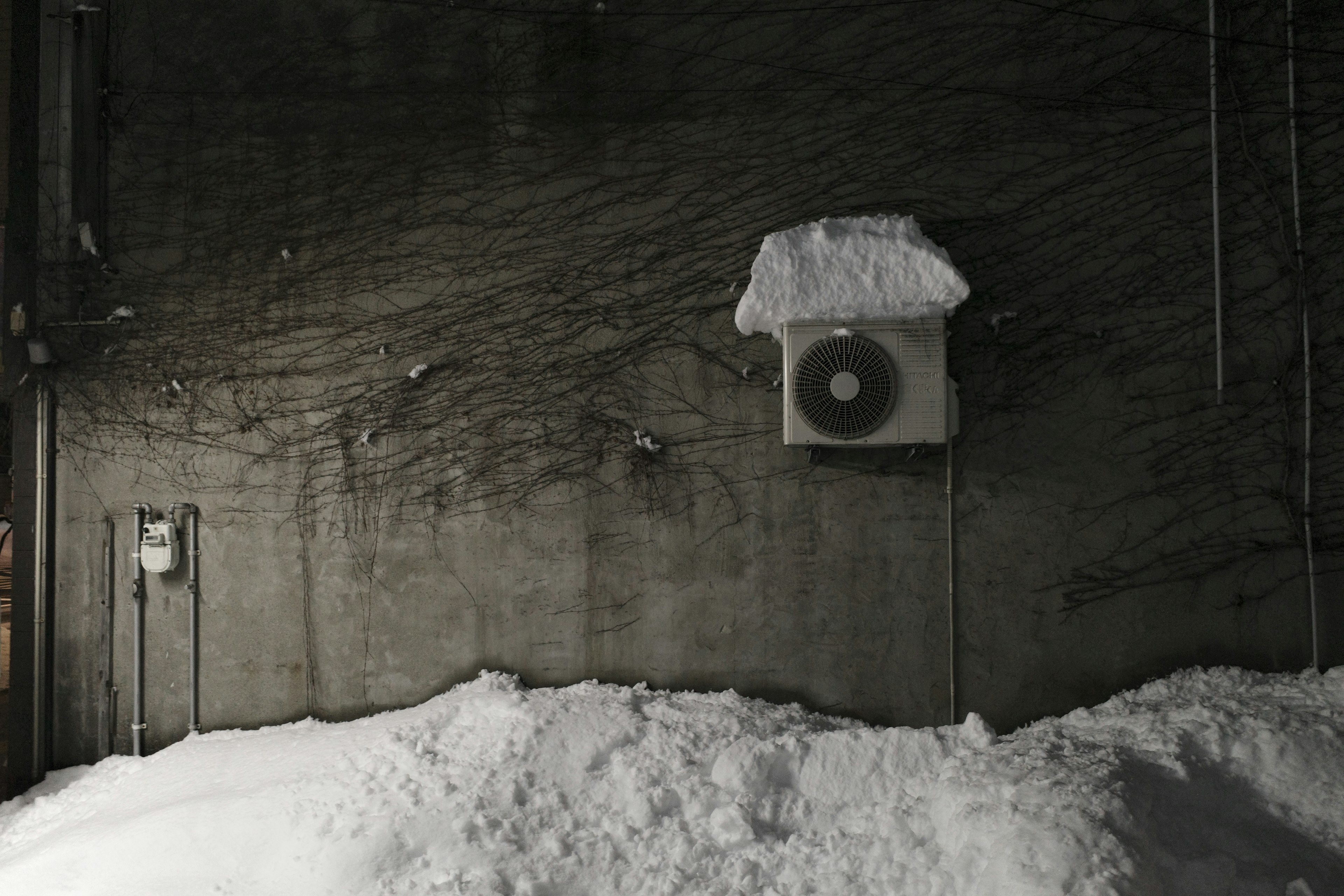 Air conditioner covered in snow against a dark wall