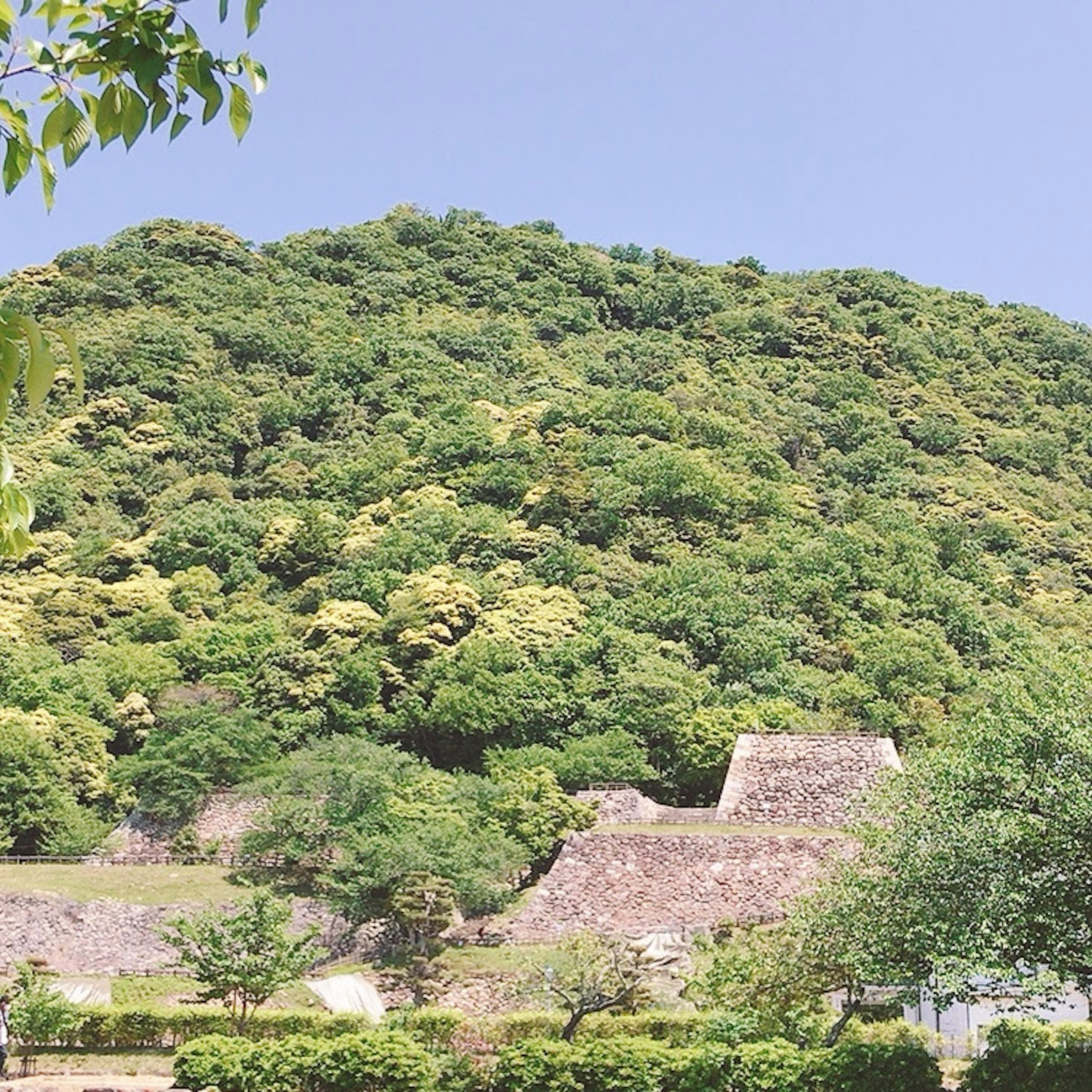 A lush green hill with ancient ruins visible in the foreground