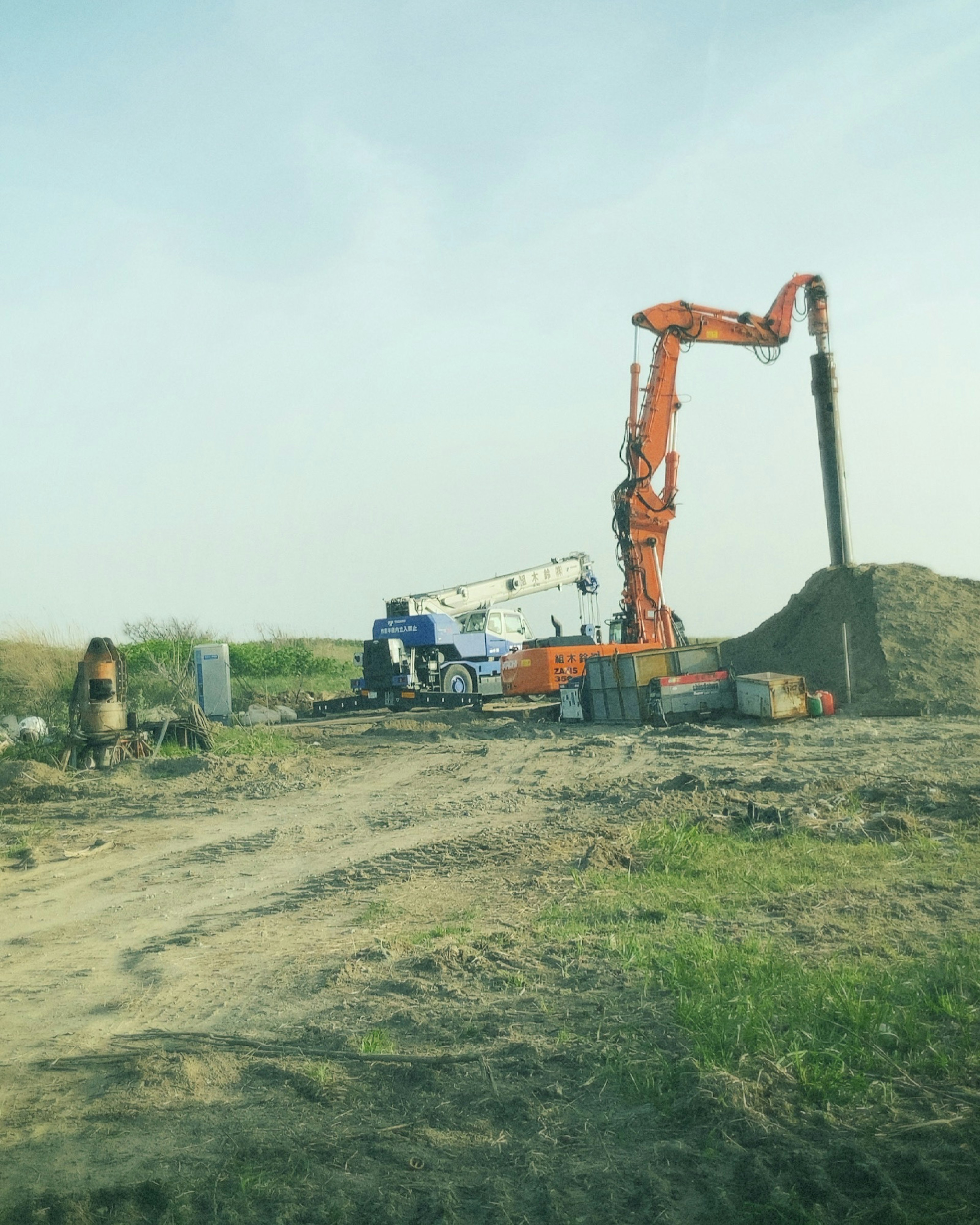 Construction site with an orange crane digging soil