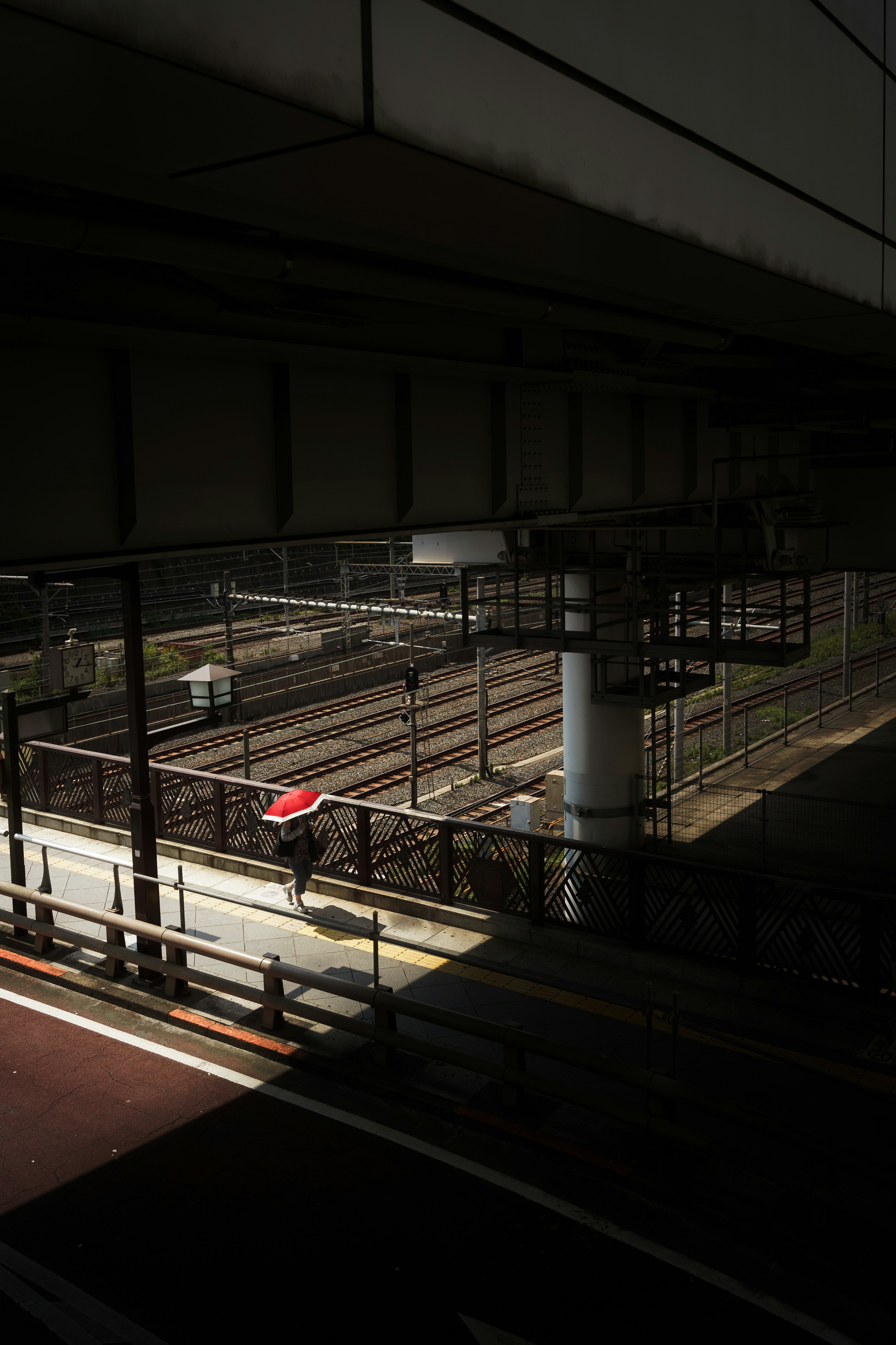 View of railway tracks under a dark station with shadows