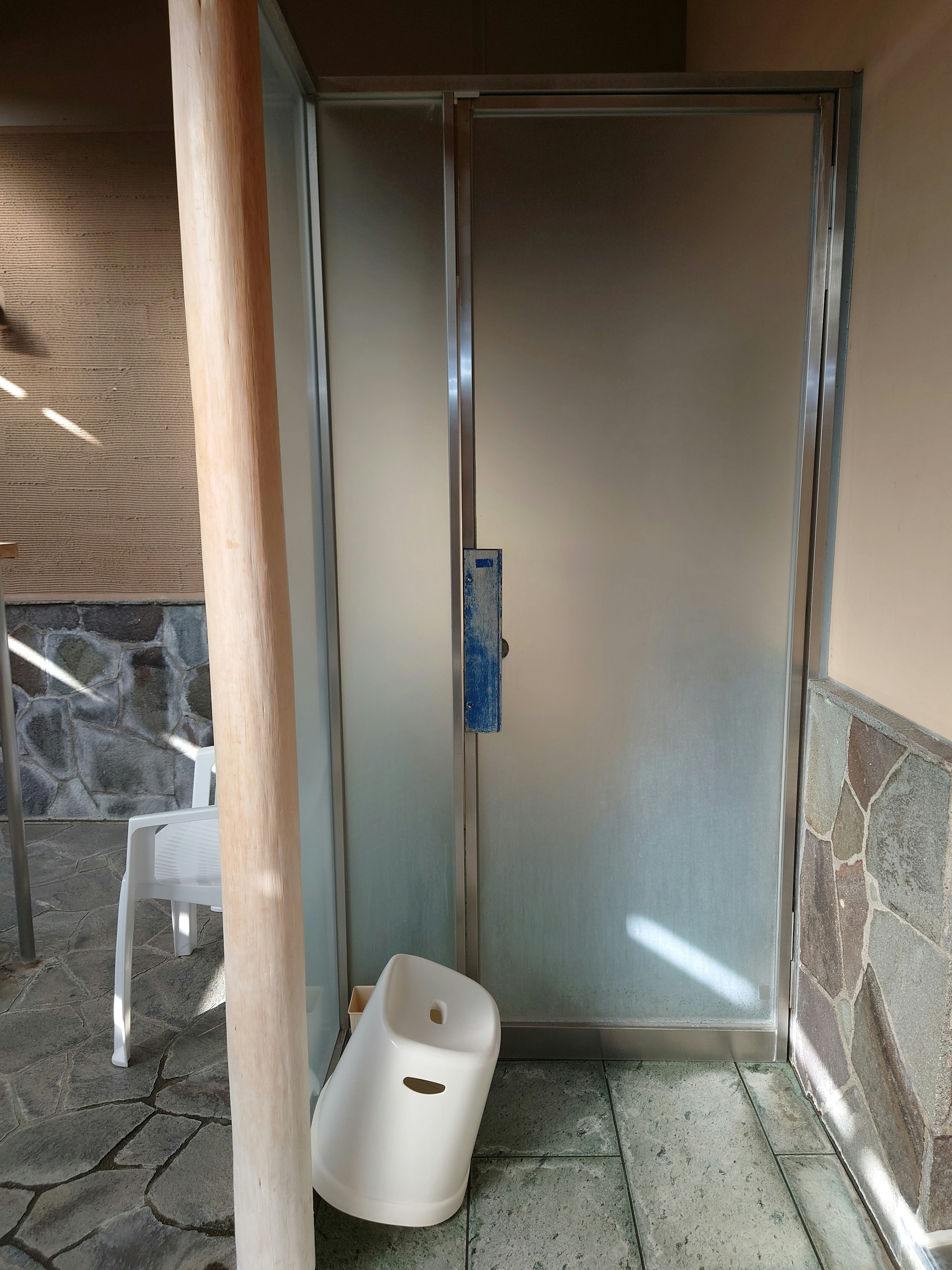 Bathroom corner featuring a frosted shower door and stone wall