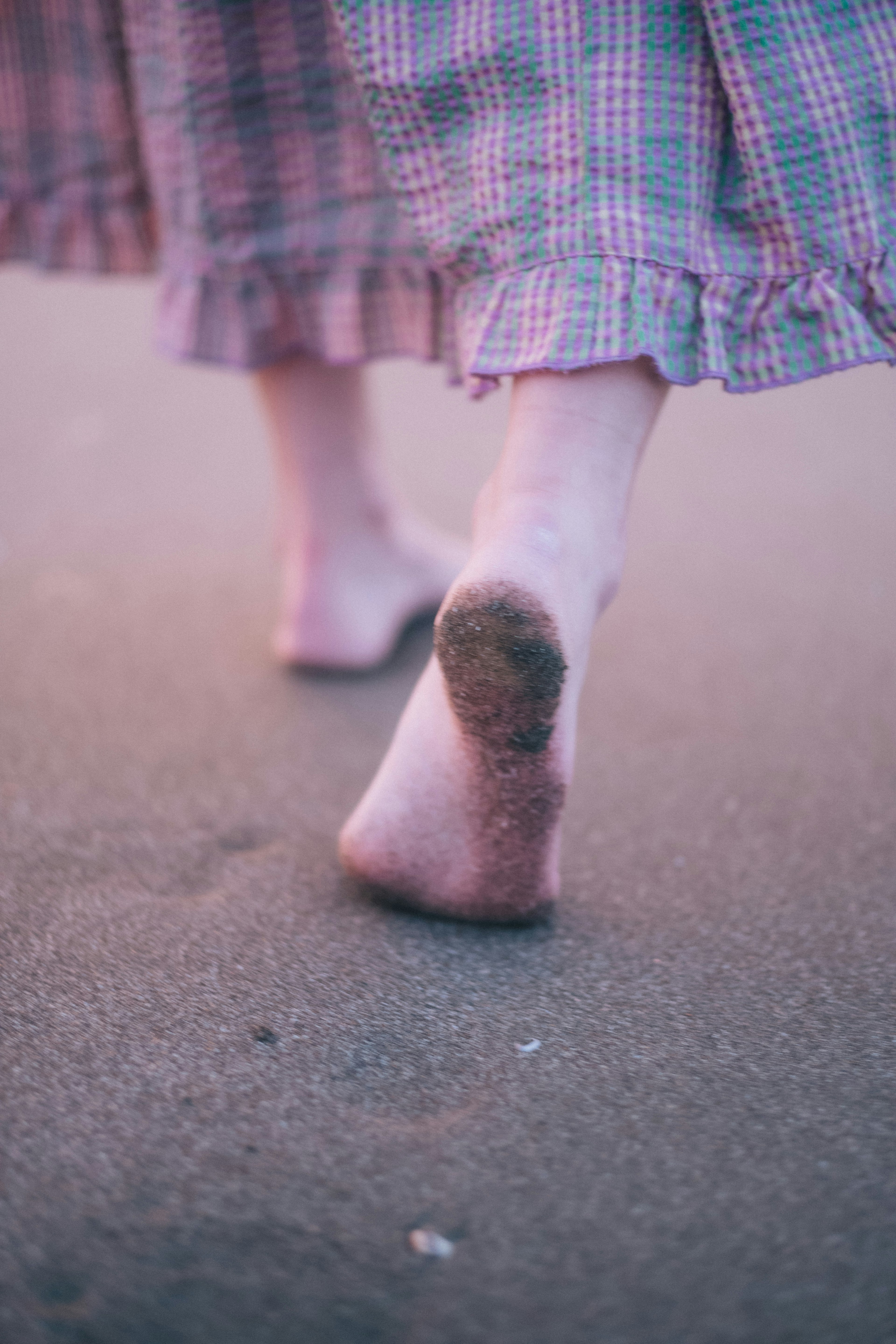 Piedi nudi che camminano sulla spiaggia con una gonna a quadretti