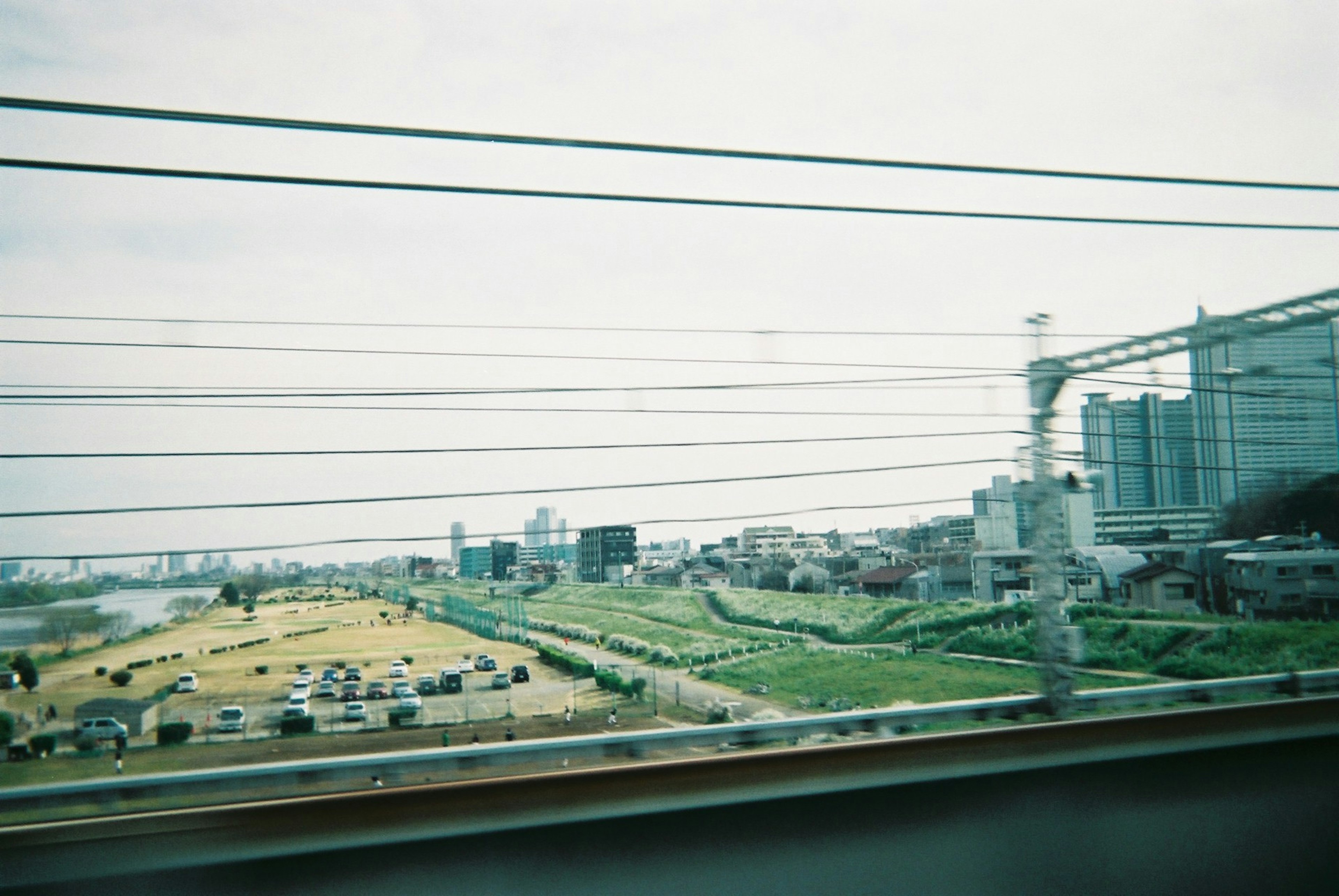 電車からの風景で、草原とビルが見える