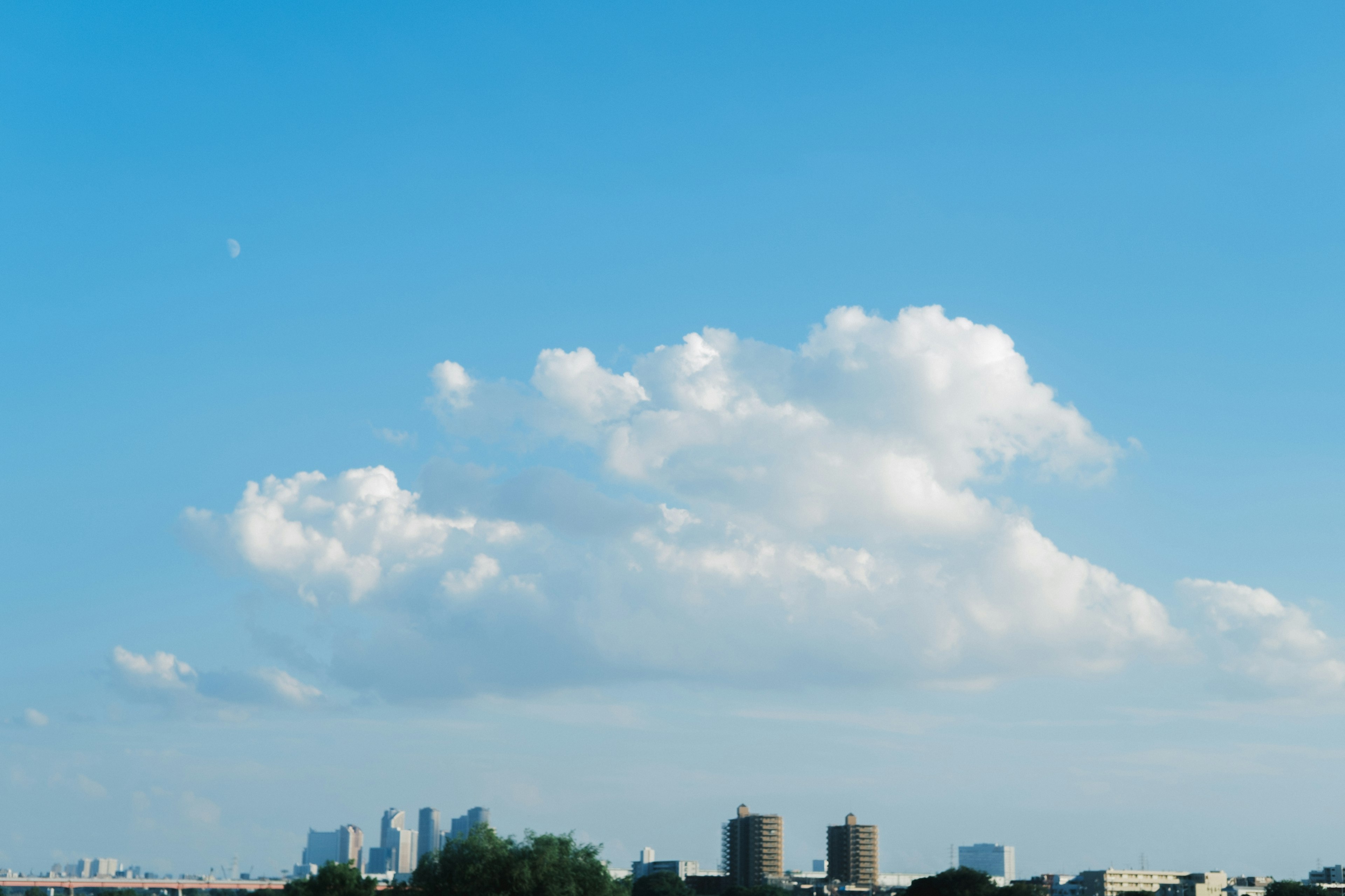 Fluffige weiße Wolken in einem blauen Himmel mit Stadtsilhouette