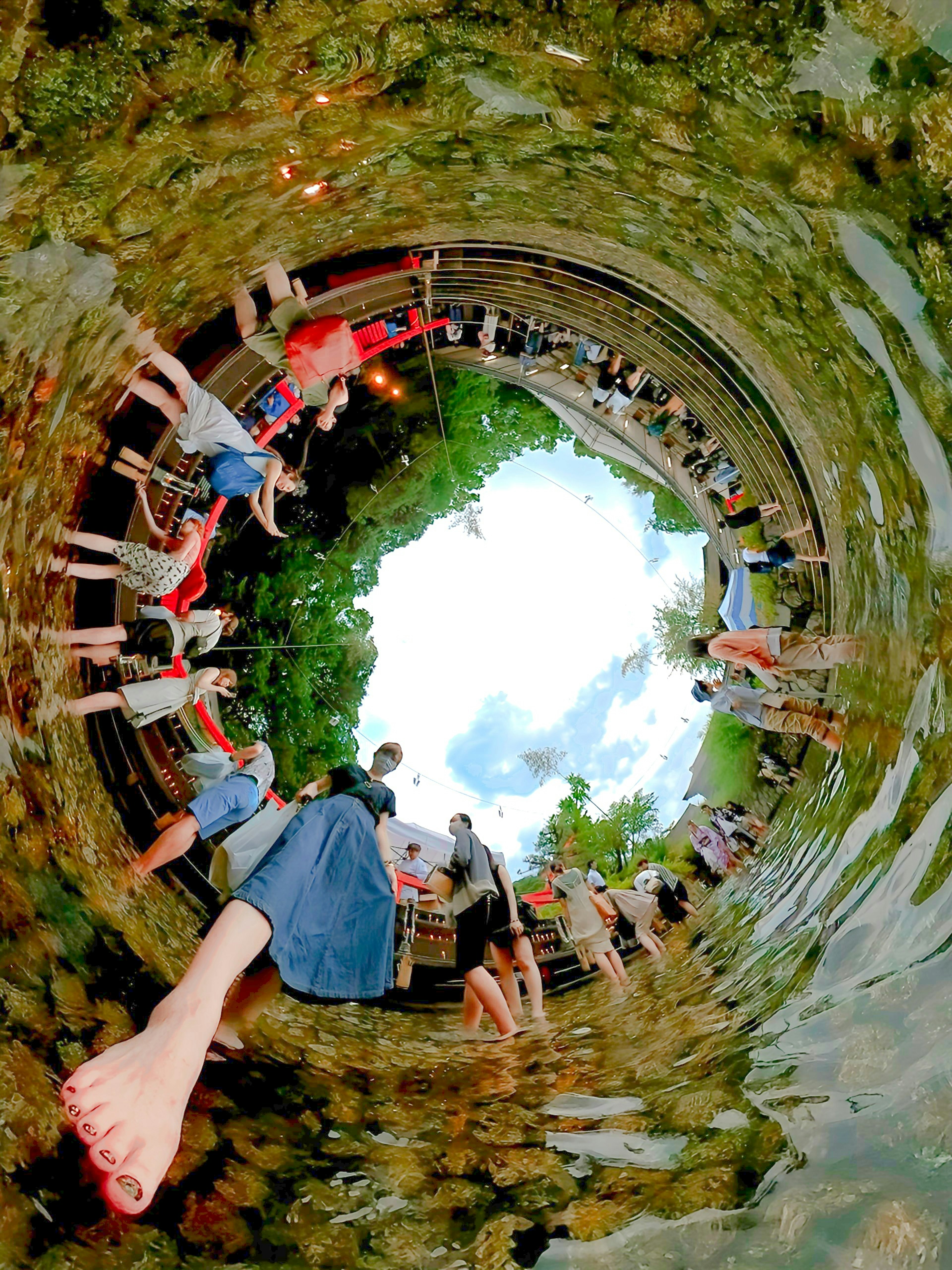 Circular image of people playing in water surrounded by natural scenery