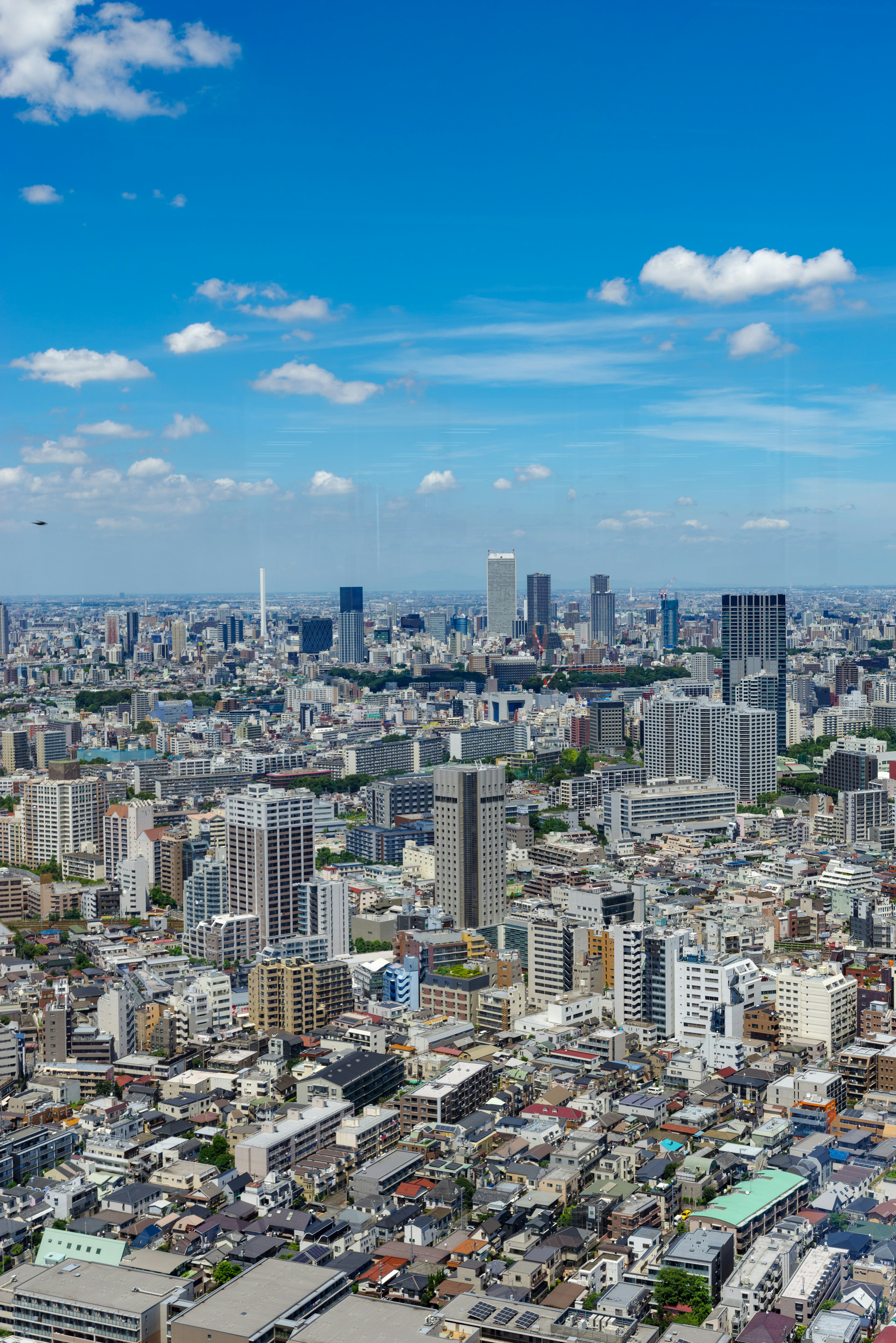 東京天際線的全景，摩天大樓在藍天和散布的雲彩下