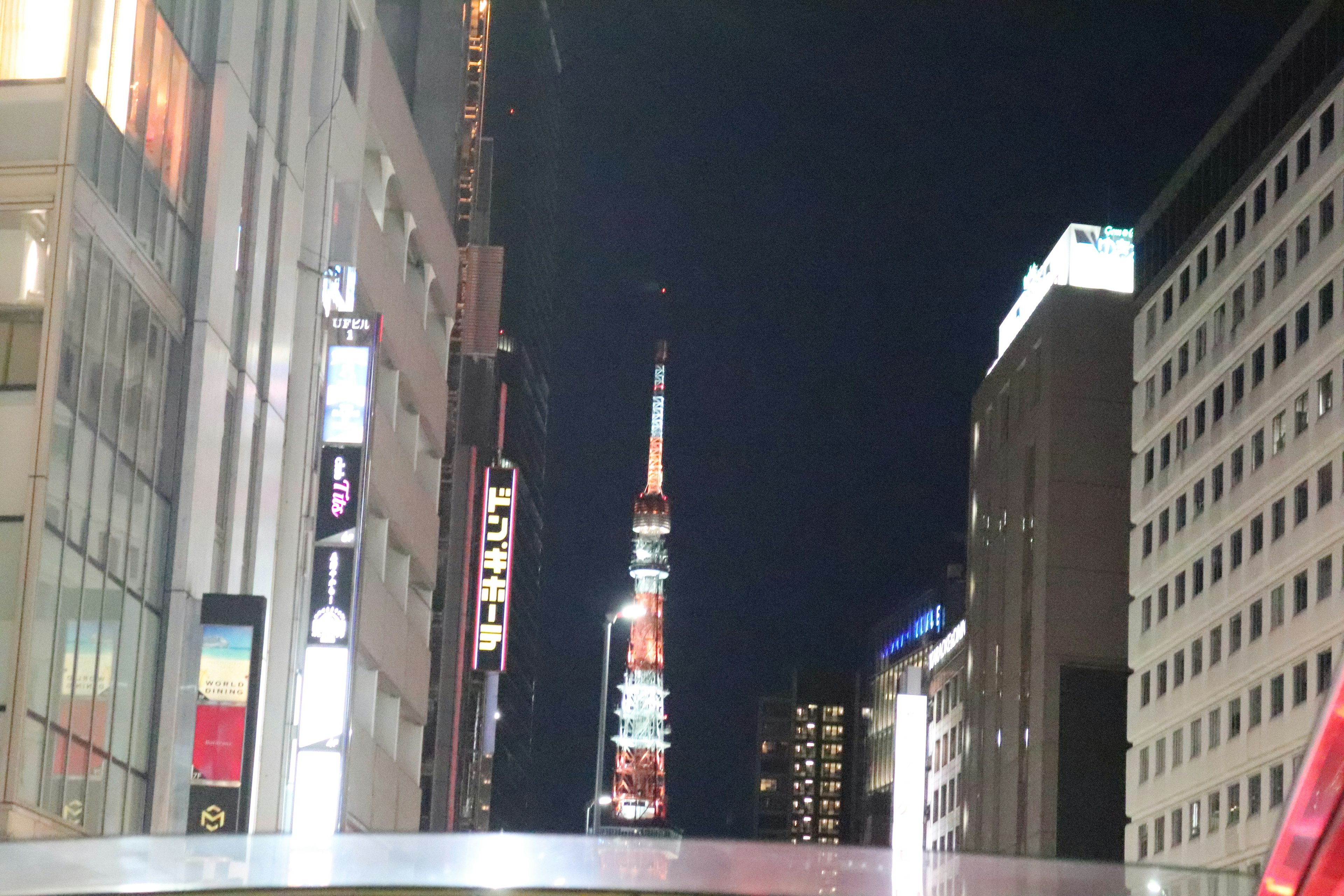 Tour de Tokyo illuminée la nuit entre les bâtiments urbains