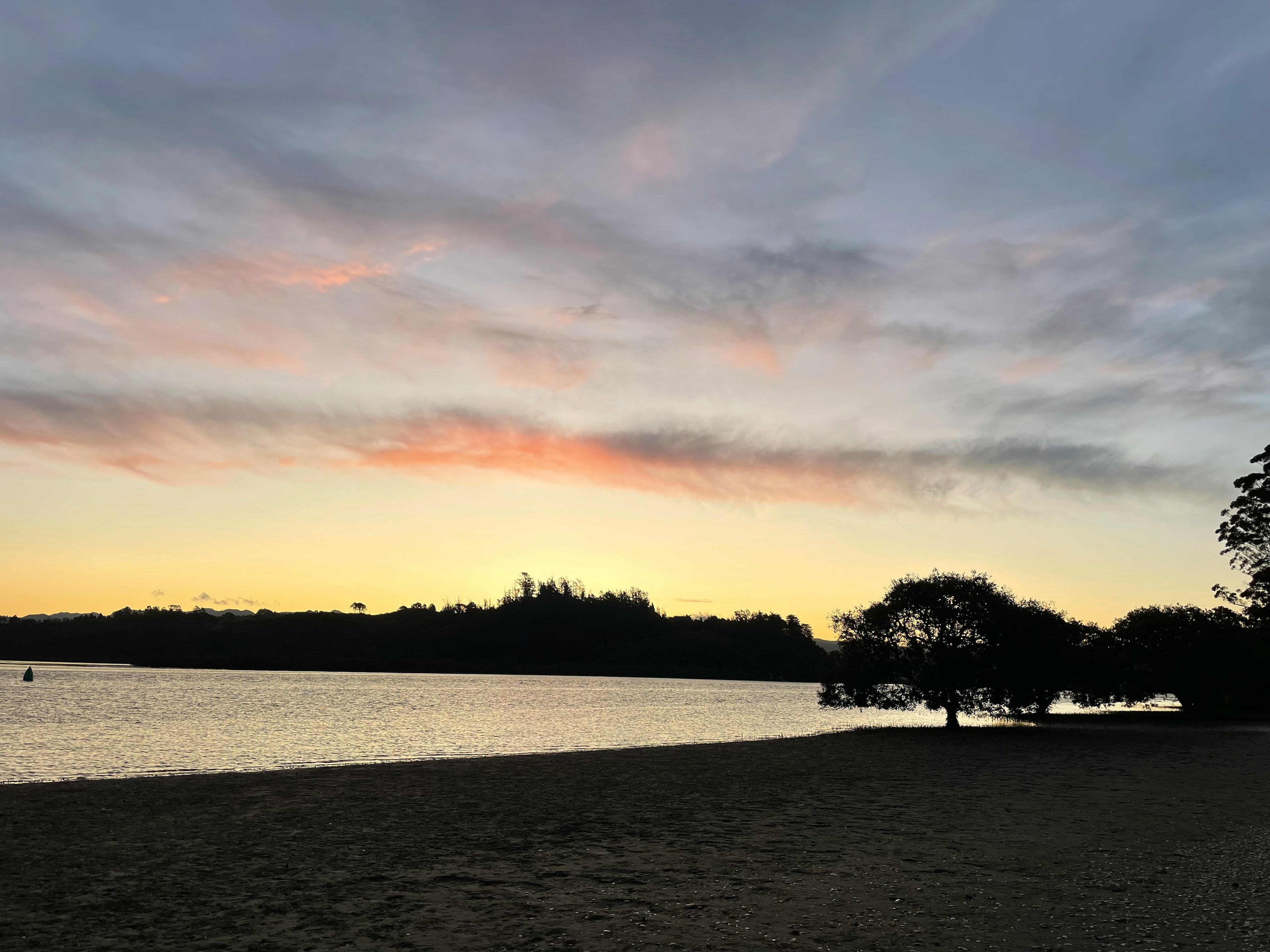 寧靜的湖邊景色，夕陽映照在水面上，遠處有山丘和樹木