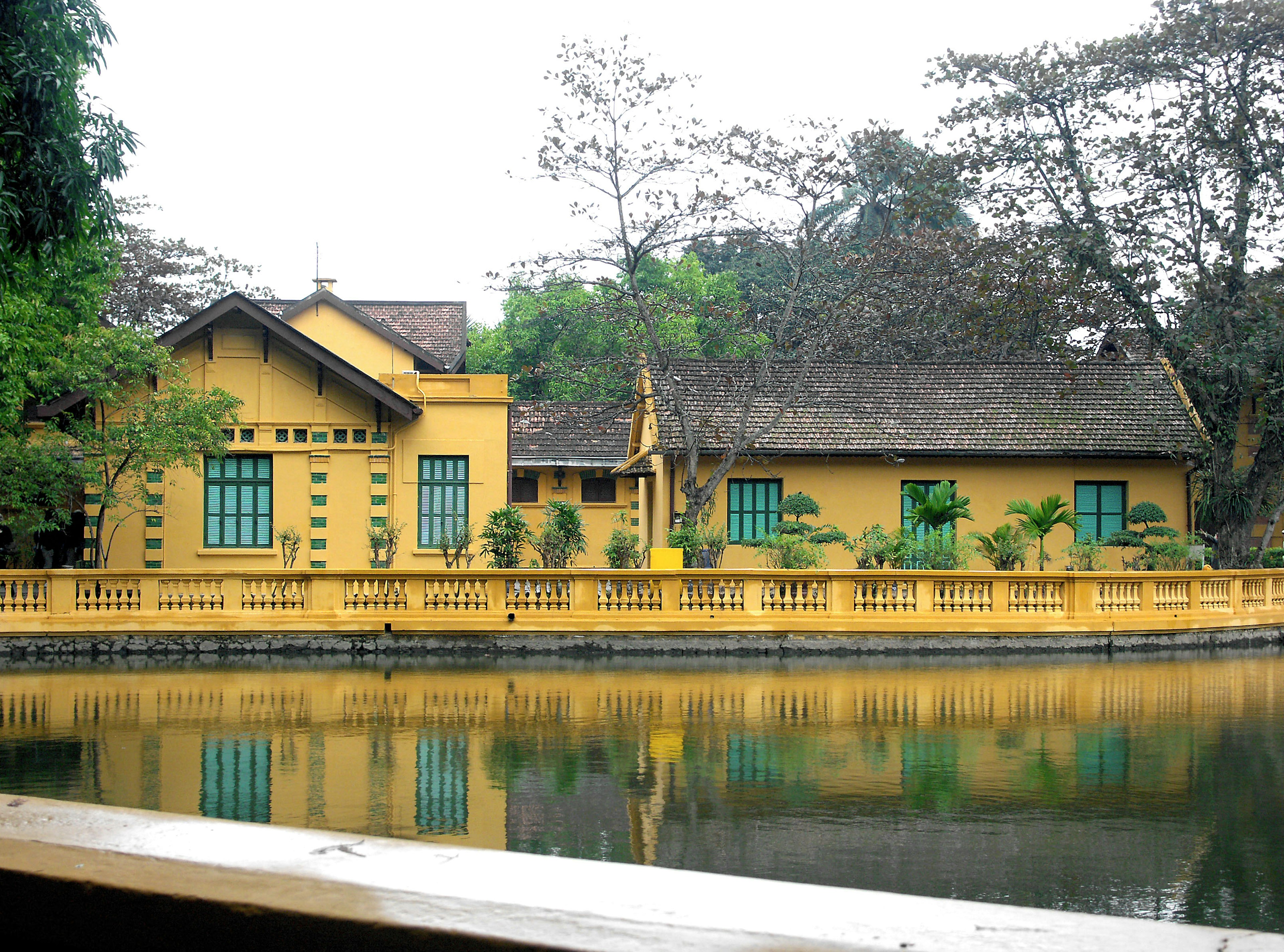 Casa gialla con finestre verdi vicino al lago