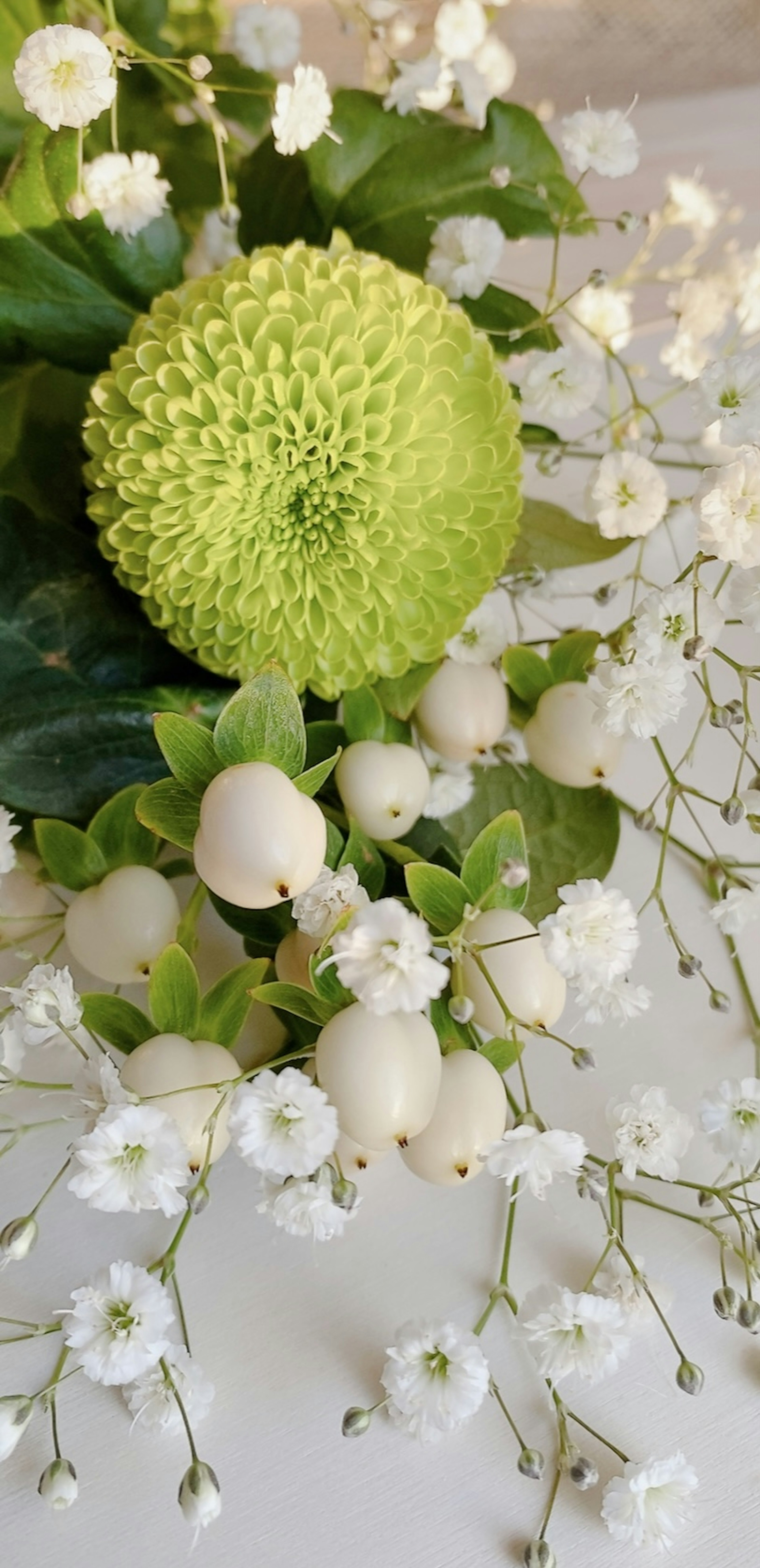 Arrangement floral avec des fleurs blanches et une fleur sphérique verte