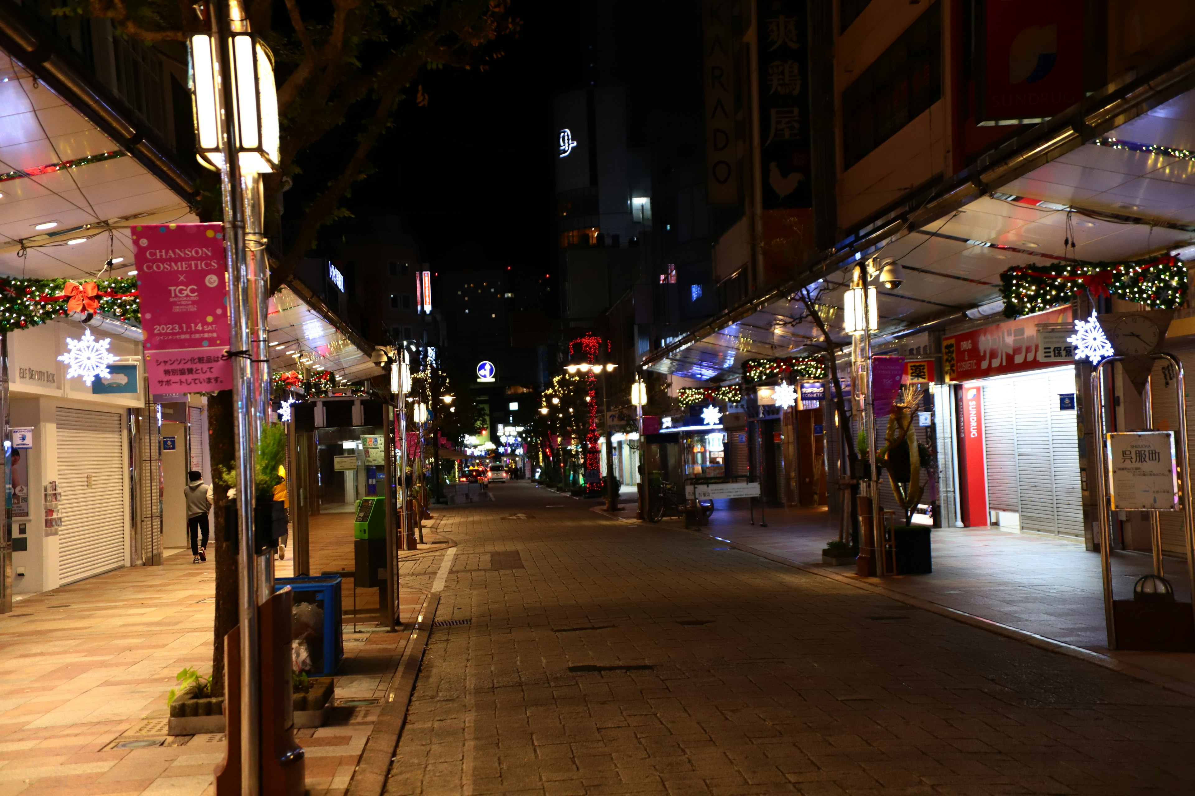 Quiet street in a shopping district at night adorned with decorative lights