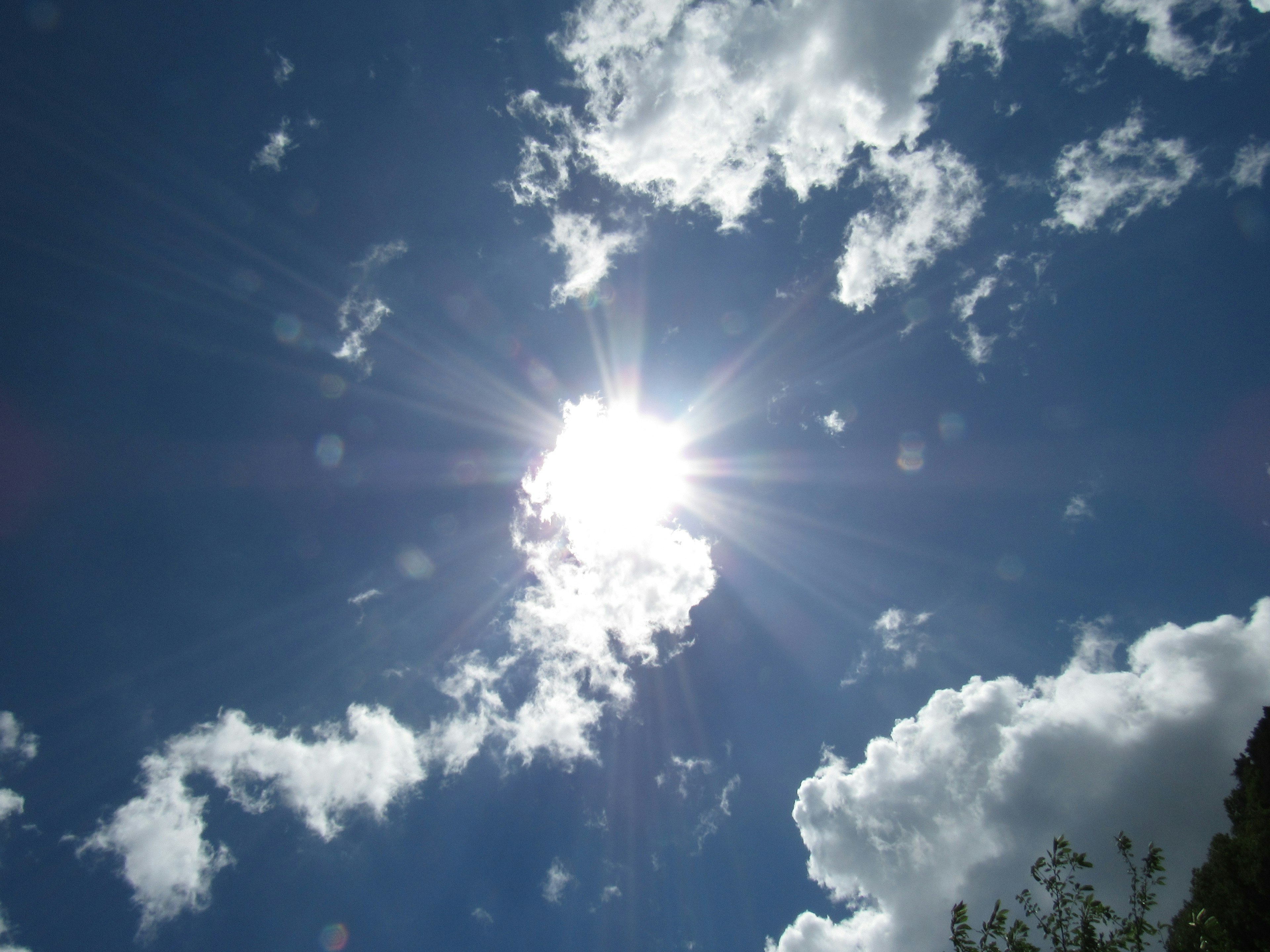 Bright sun shining through clouds in a blue sky