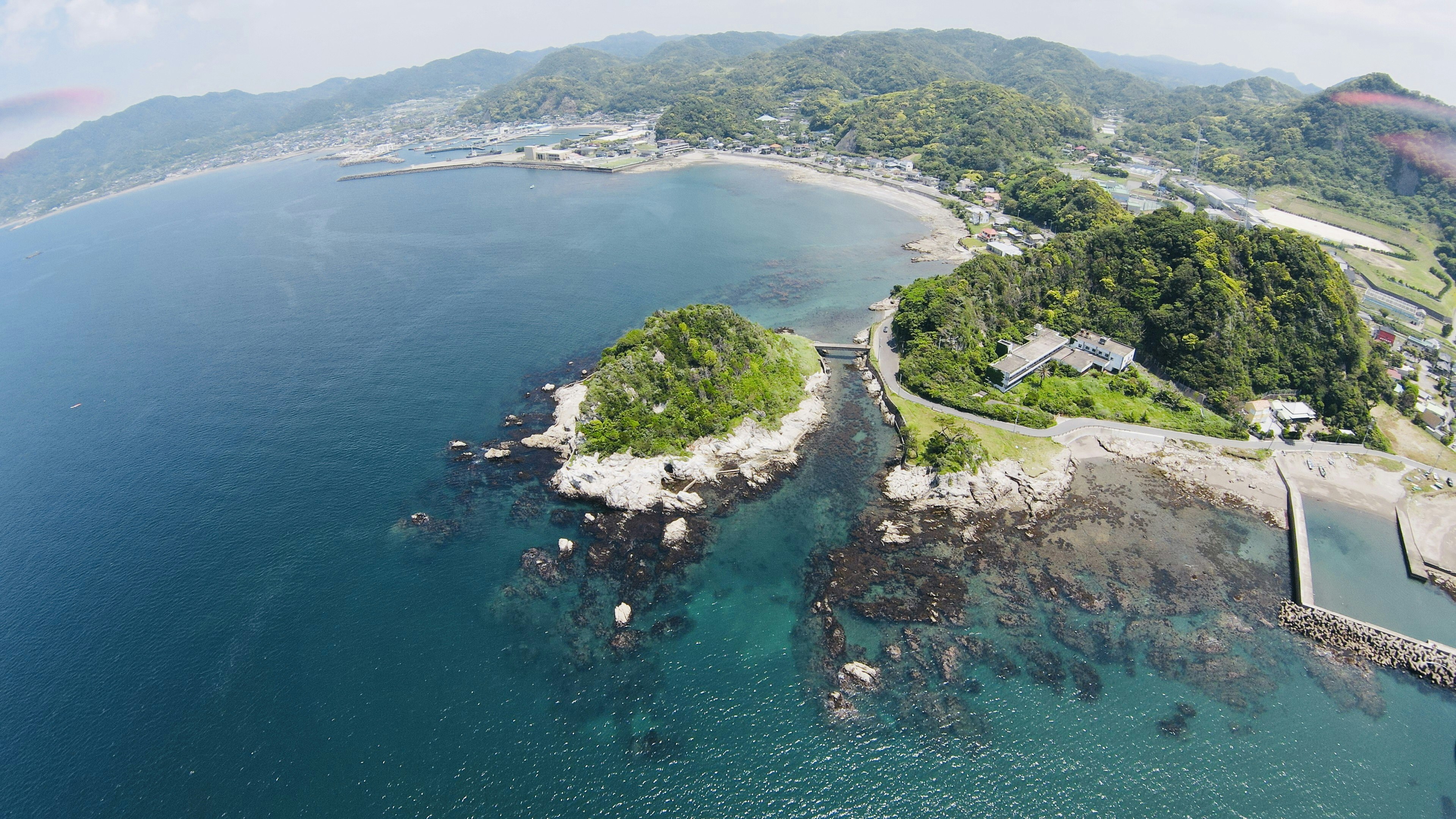 Aerial view of a lush green island surrounded by blue water with a coastal area