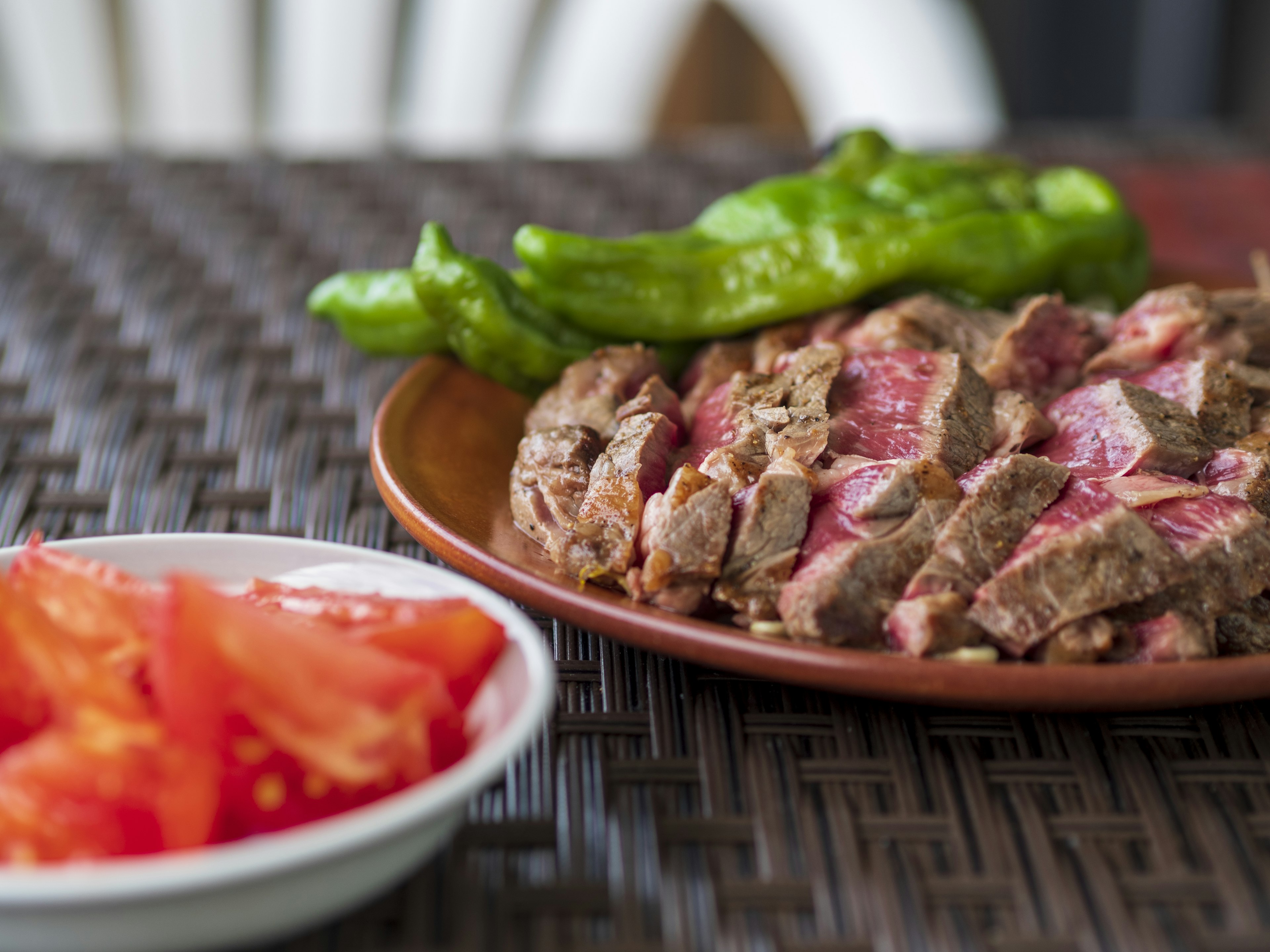 Steak tranché servi avec des tomates fraîches et des poivrons verts