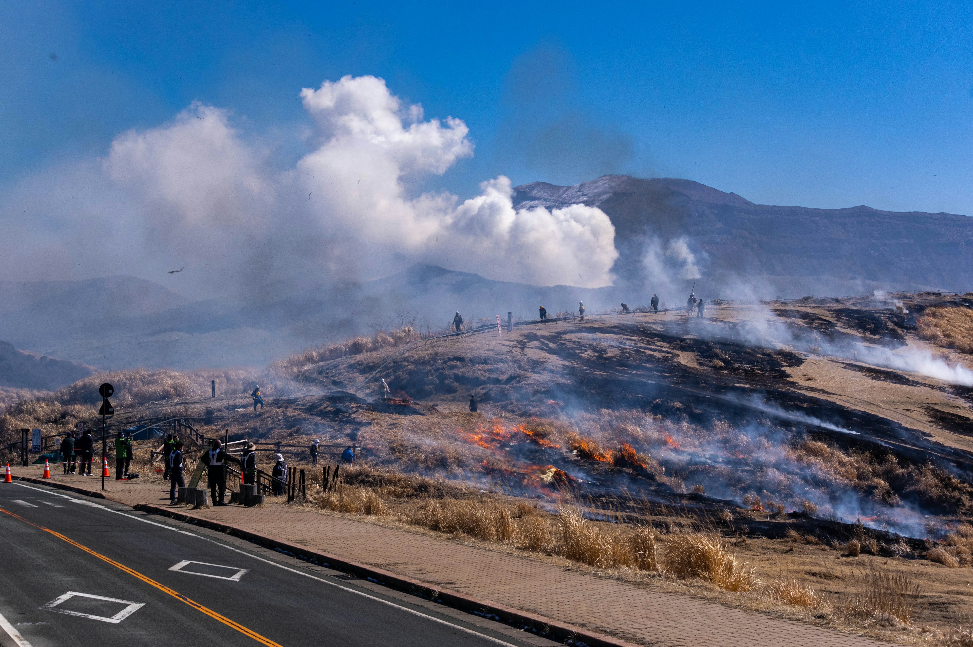 Paisaje de un incendio forestal con humo y personas reunidas