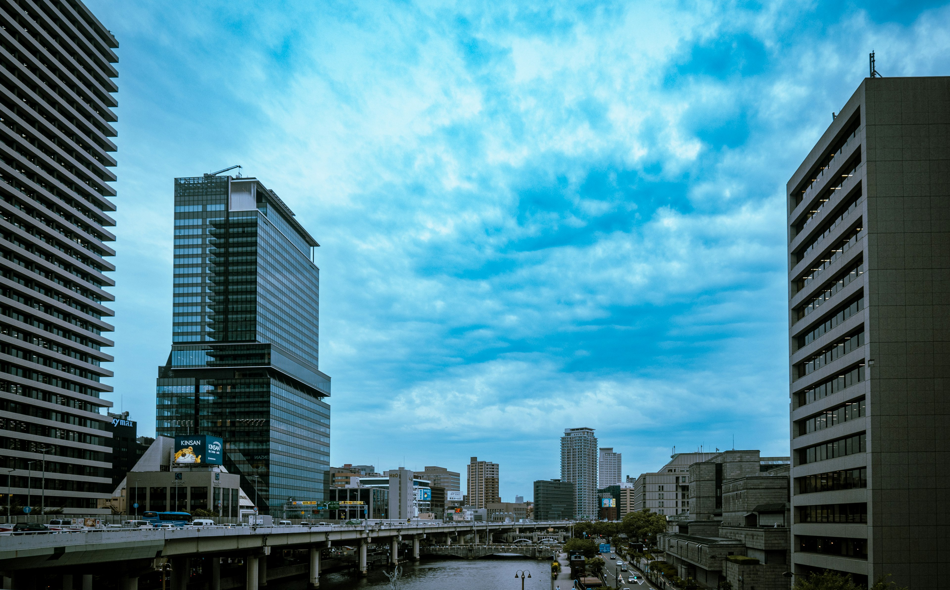 Stadtansicht mit modernen Wolkenkratzern und einem Fluss unter blauem Himmel