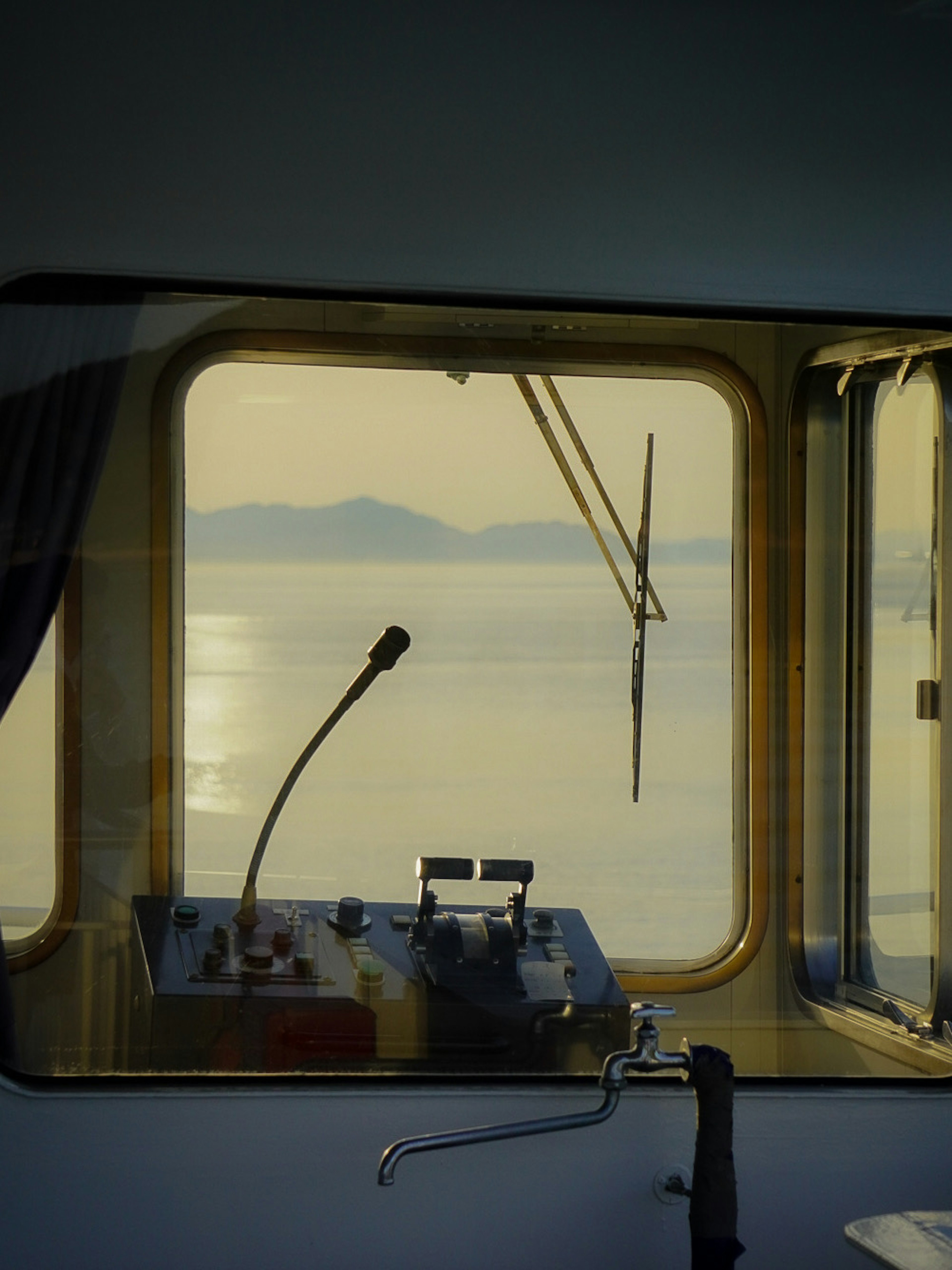 View of the sea from a ship's control room featuring a microphone and control panel