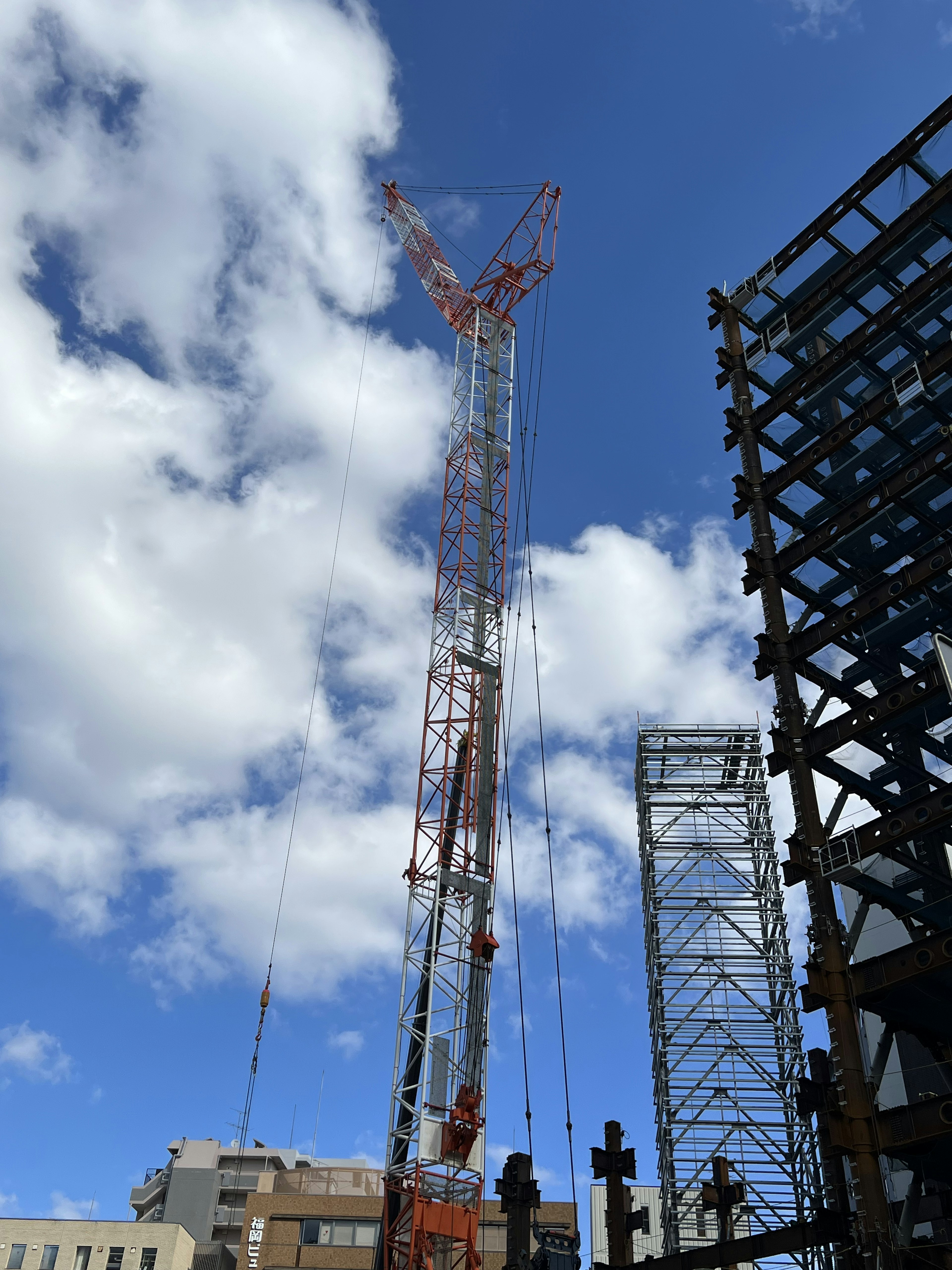 Grue de construction haute contre un ciel bleu avec des nuages