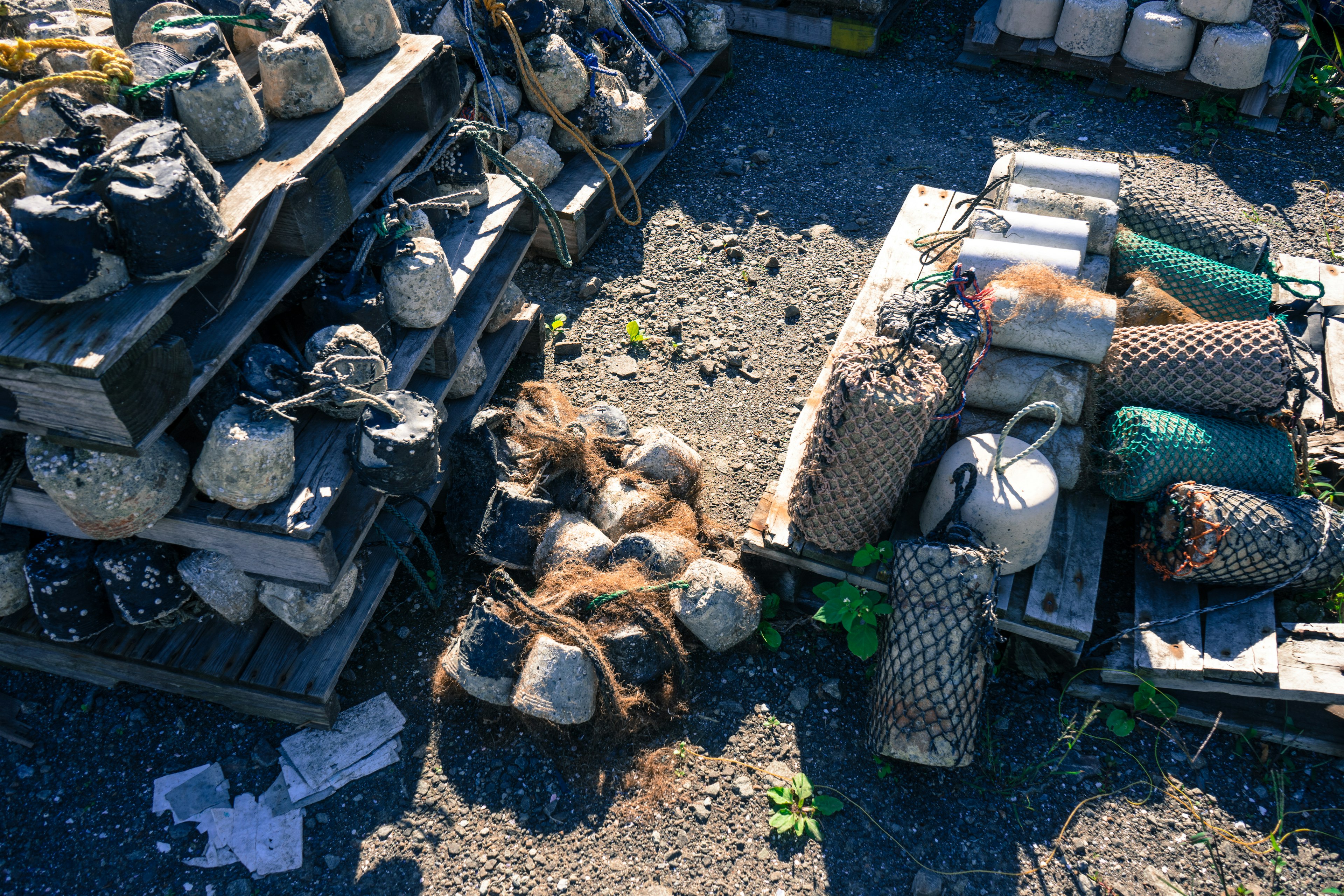 A collection of old fishing nets and gear stacked outside a warehouse