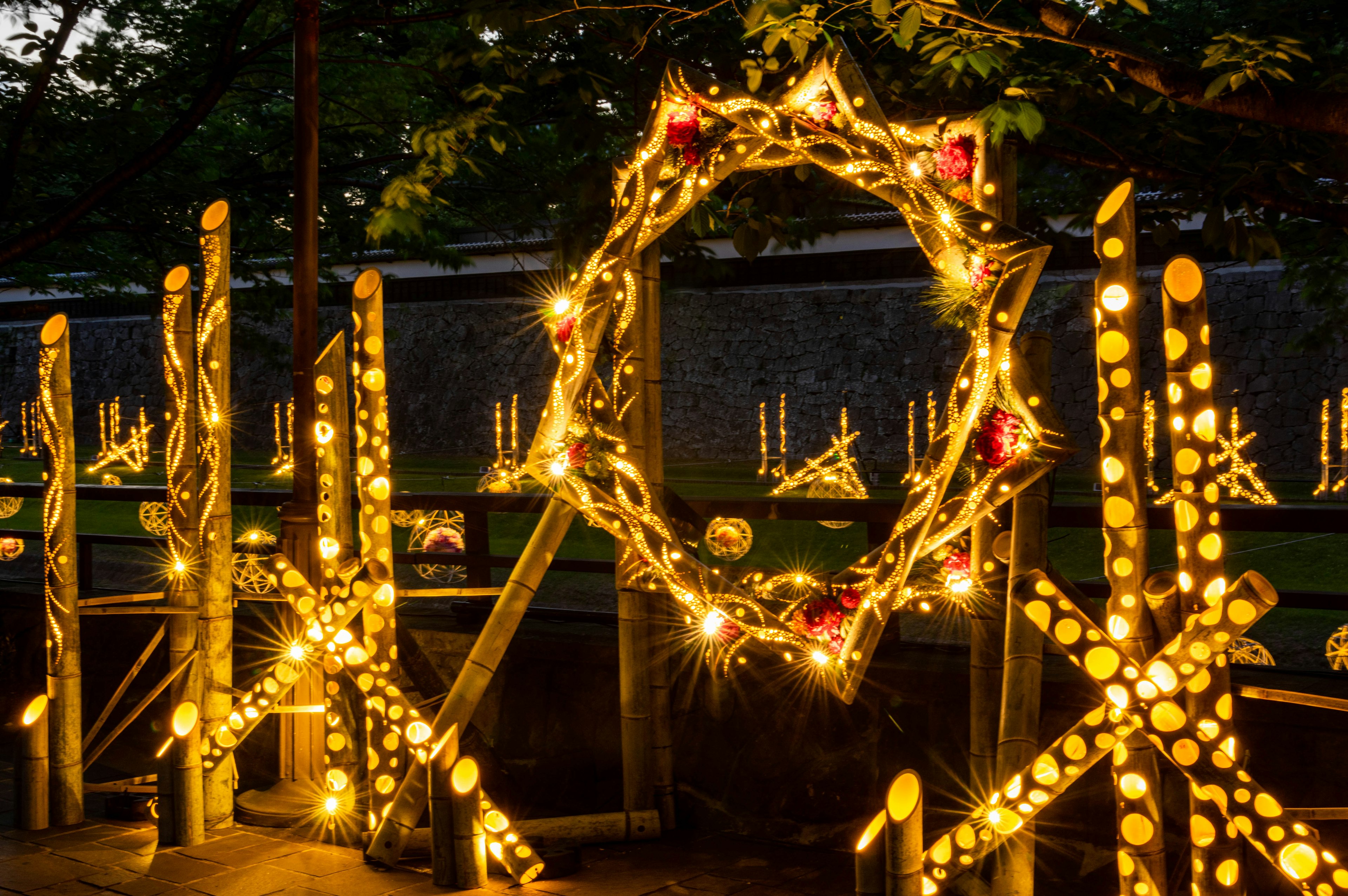 A decorated Christmas wreath with lights and star-shaped decorations in a garden