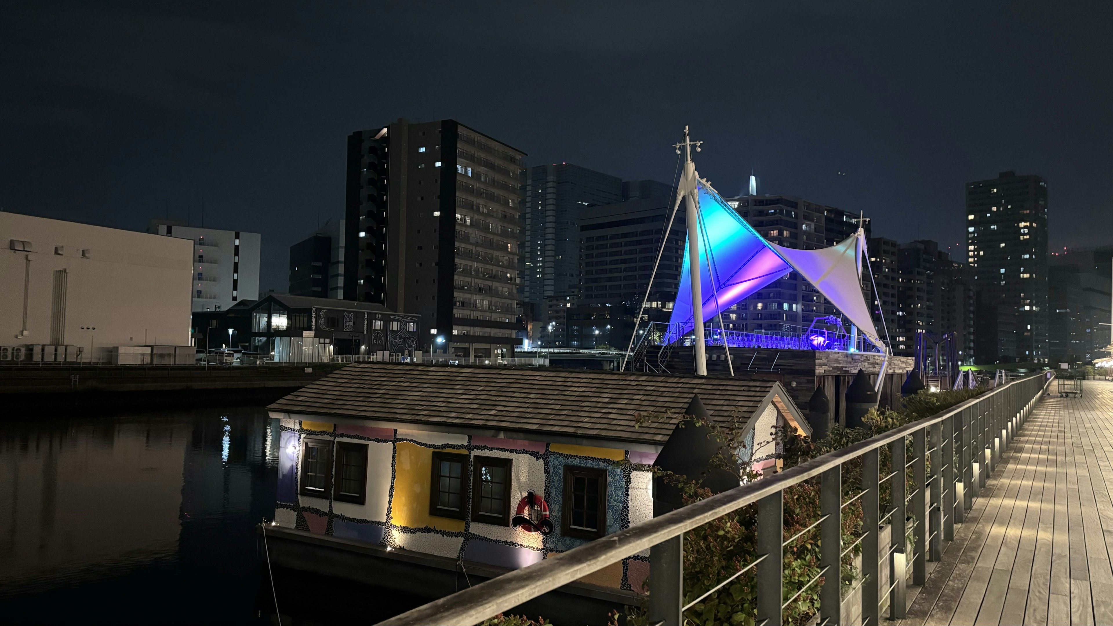 Casa galleggiante illuminata da una tenda colorata lungo il fiume di notte