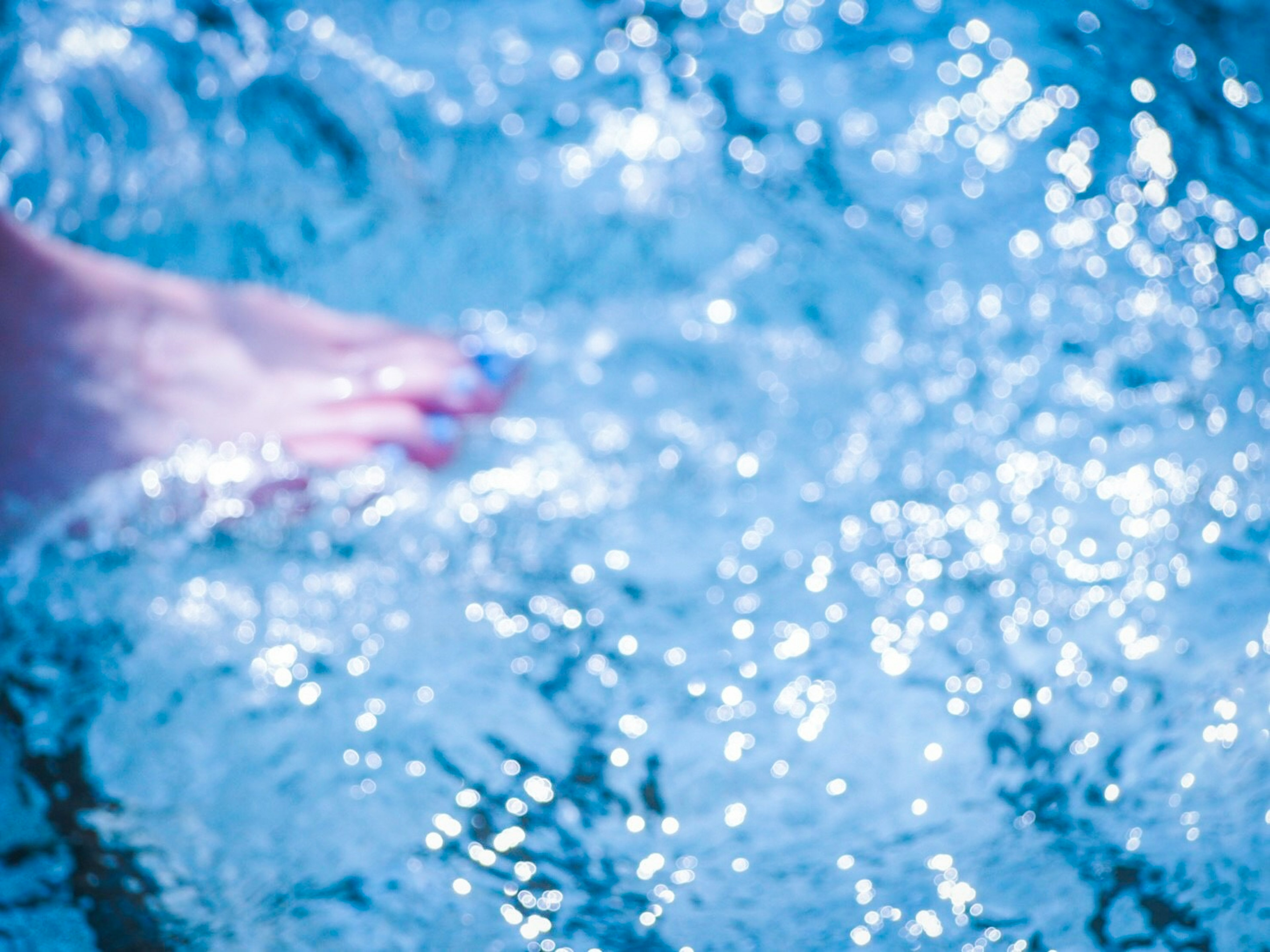 Ein Fuß berührt sanft das schimmernde blaue Wasser