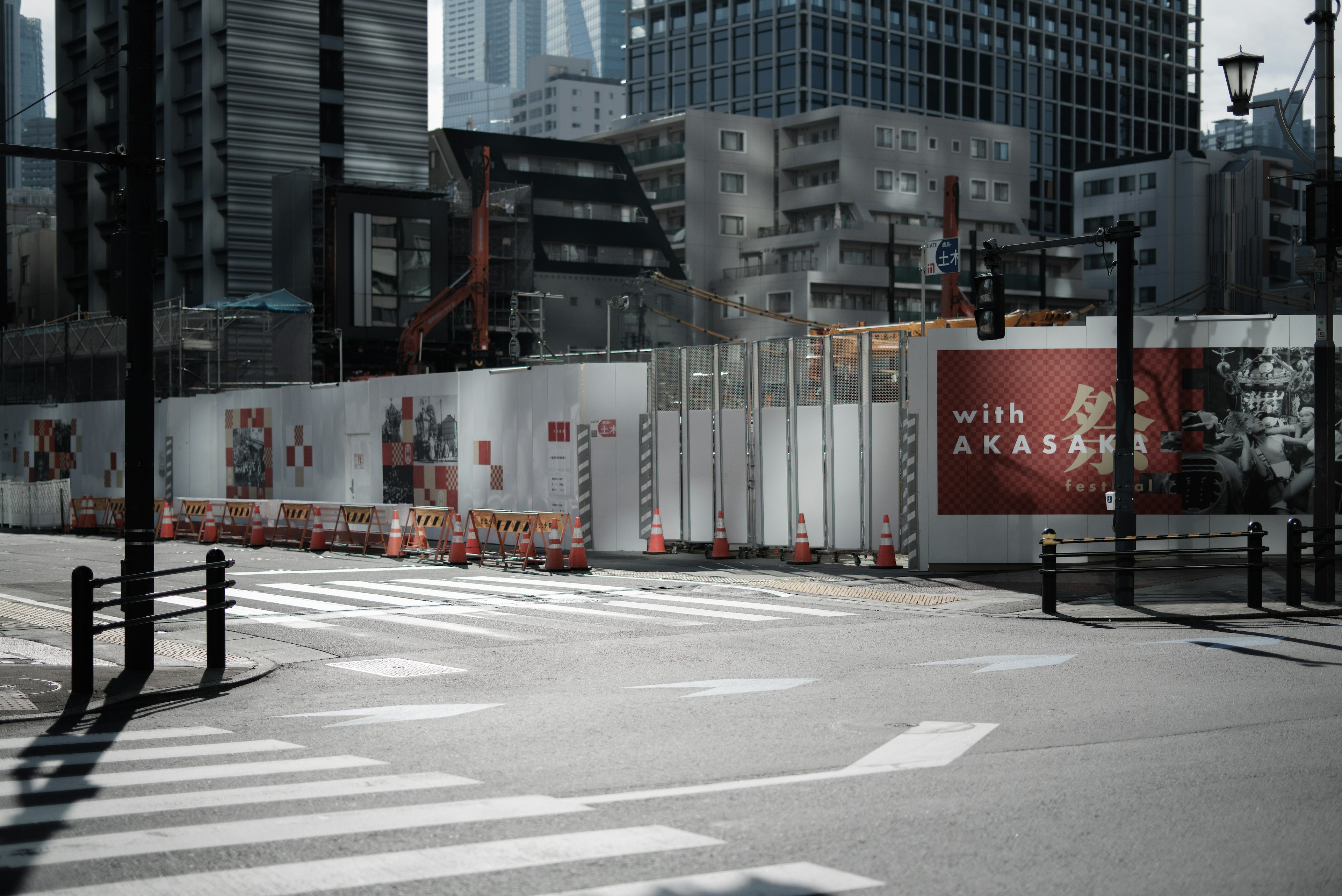 都市の工事現場が見える交差点の風景 高層ビルと白いフェンスが特徴