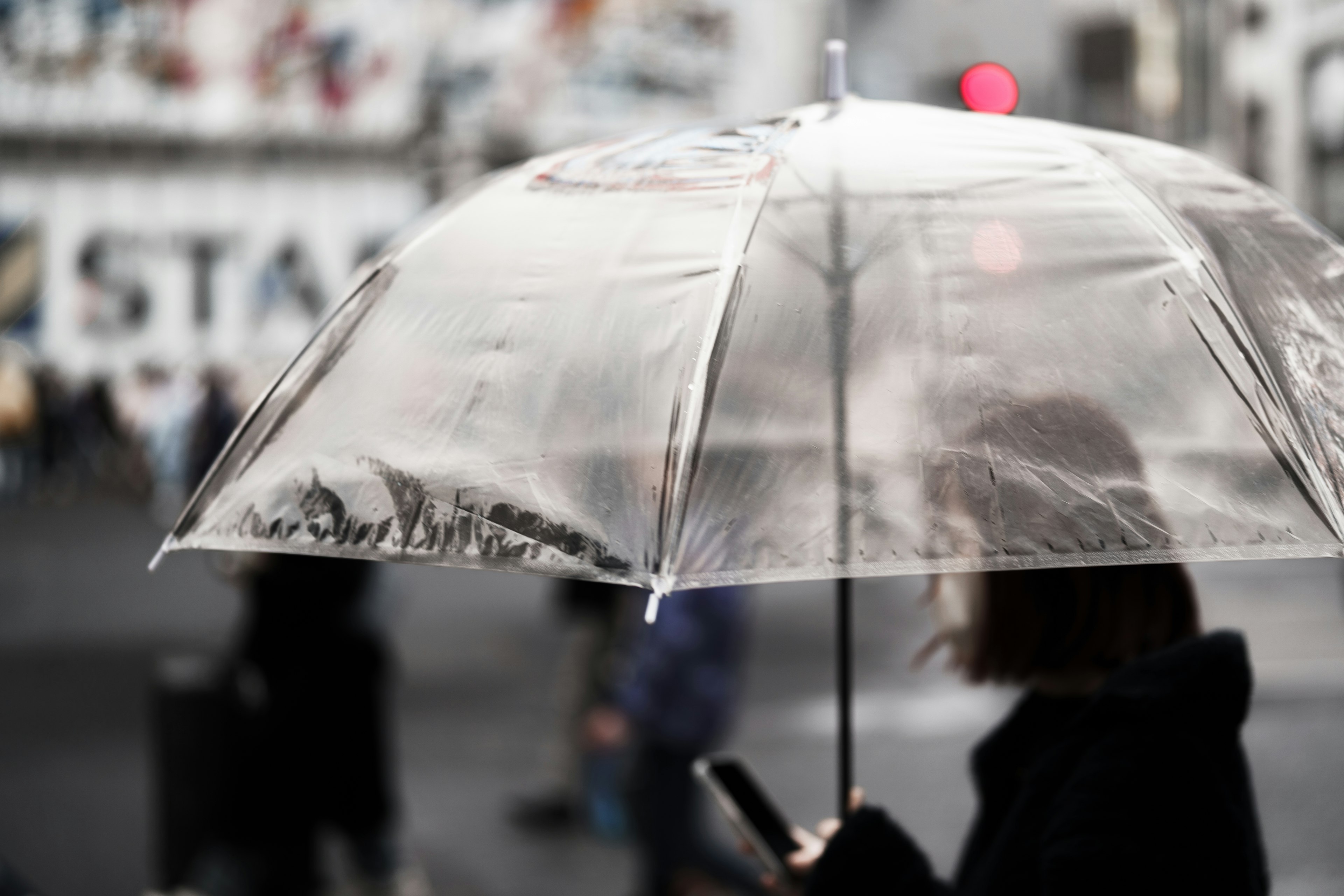 A person holding a transparent umbrella standing in the street