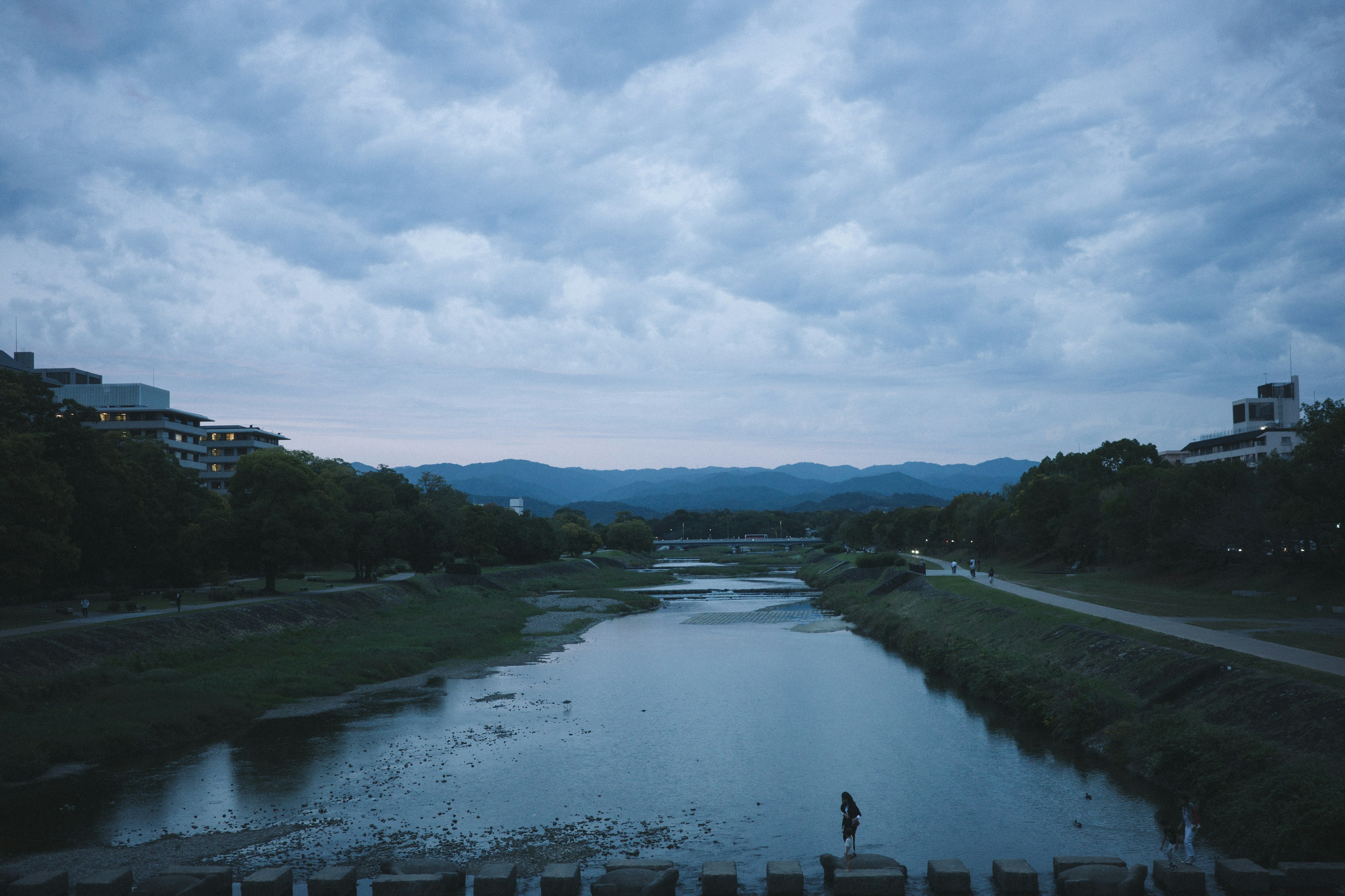 A serene river landscape with mountains and cloudy sky