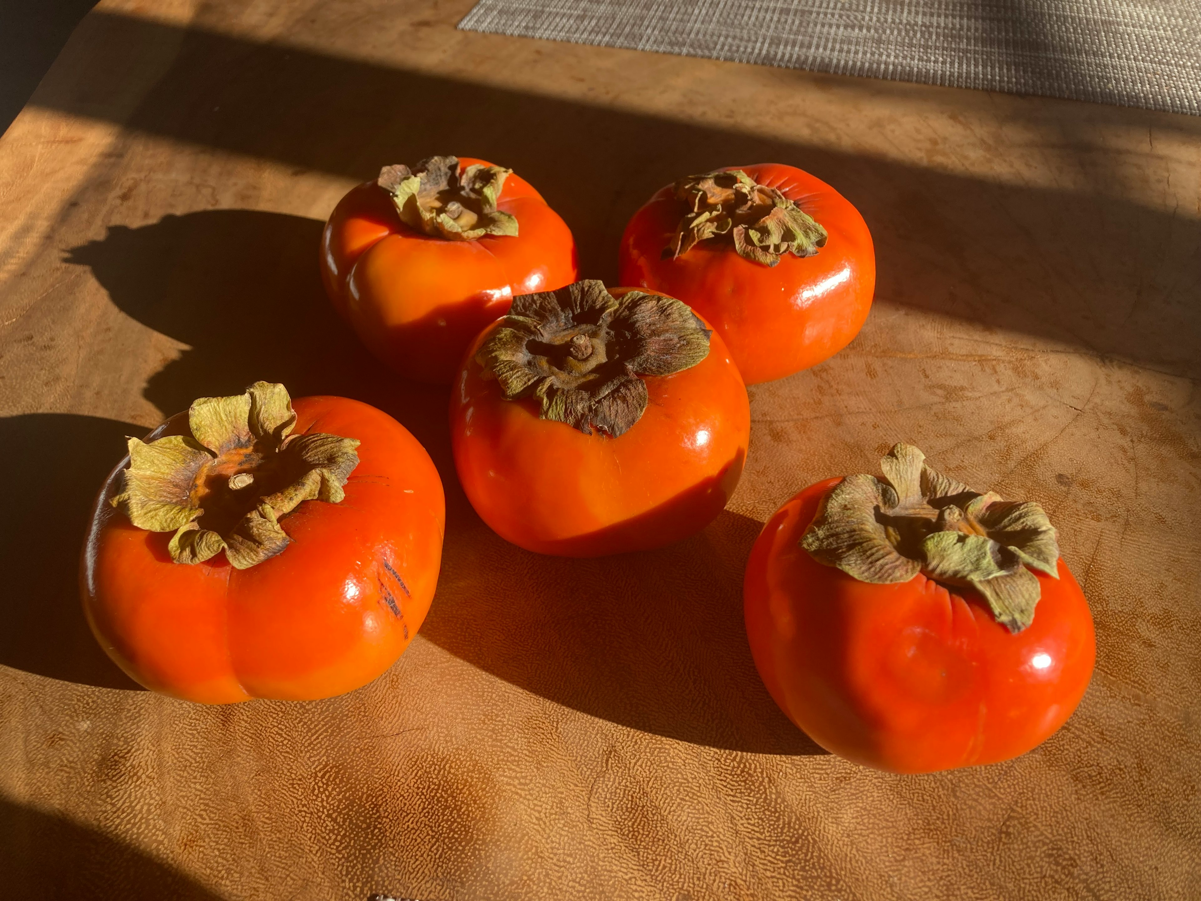 Five persimmons on a wooden table