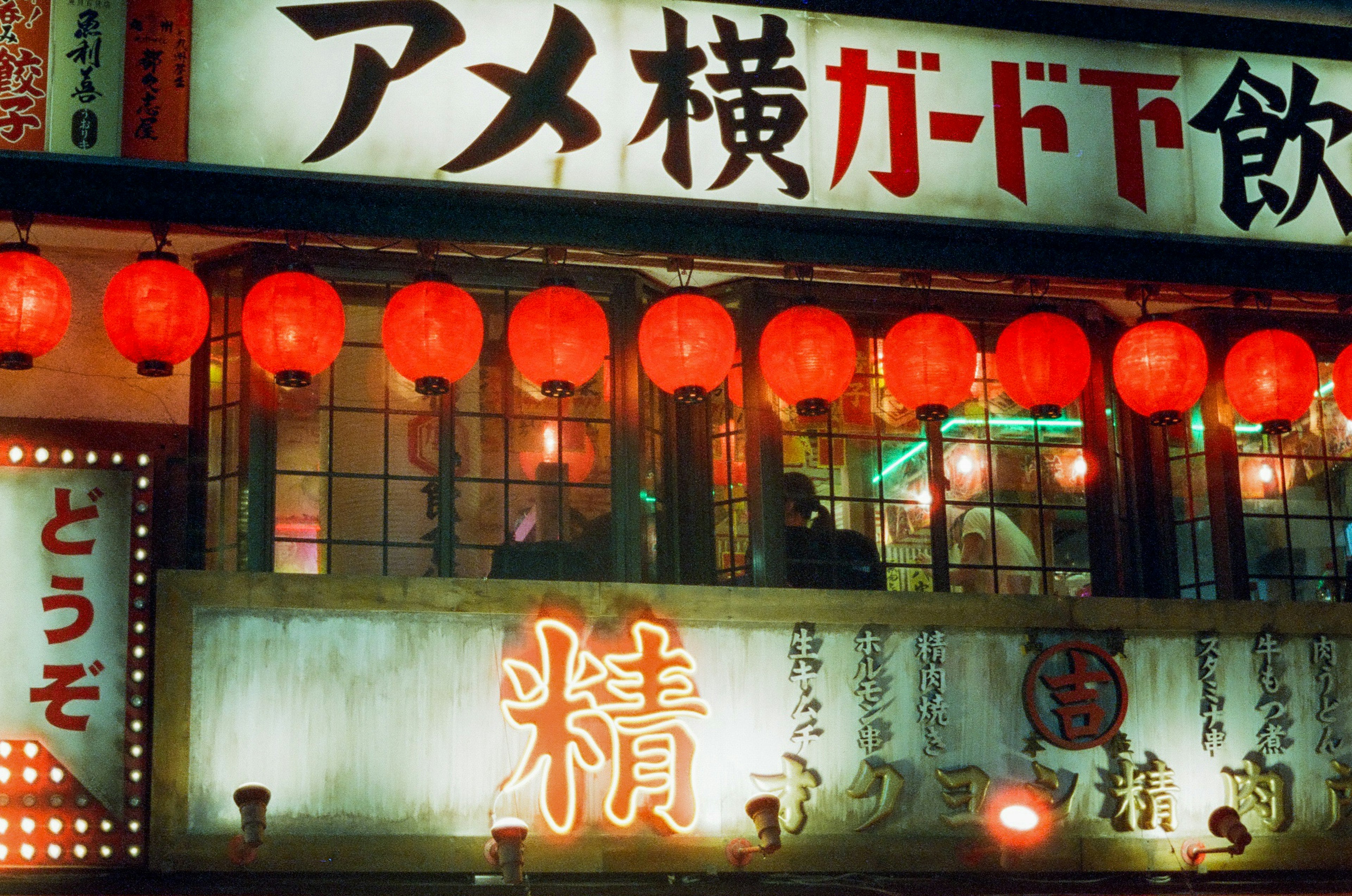 Extérieur de restaurant vibrant avec lanternes rouges affichant le panneau d'Ameyoko et du texte japonais