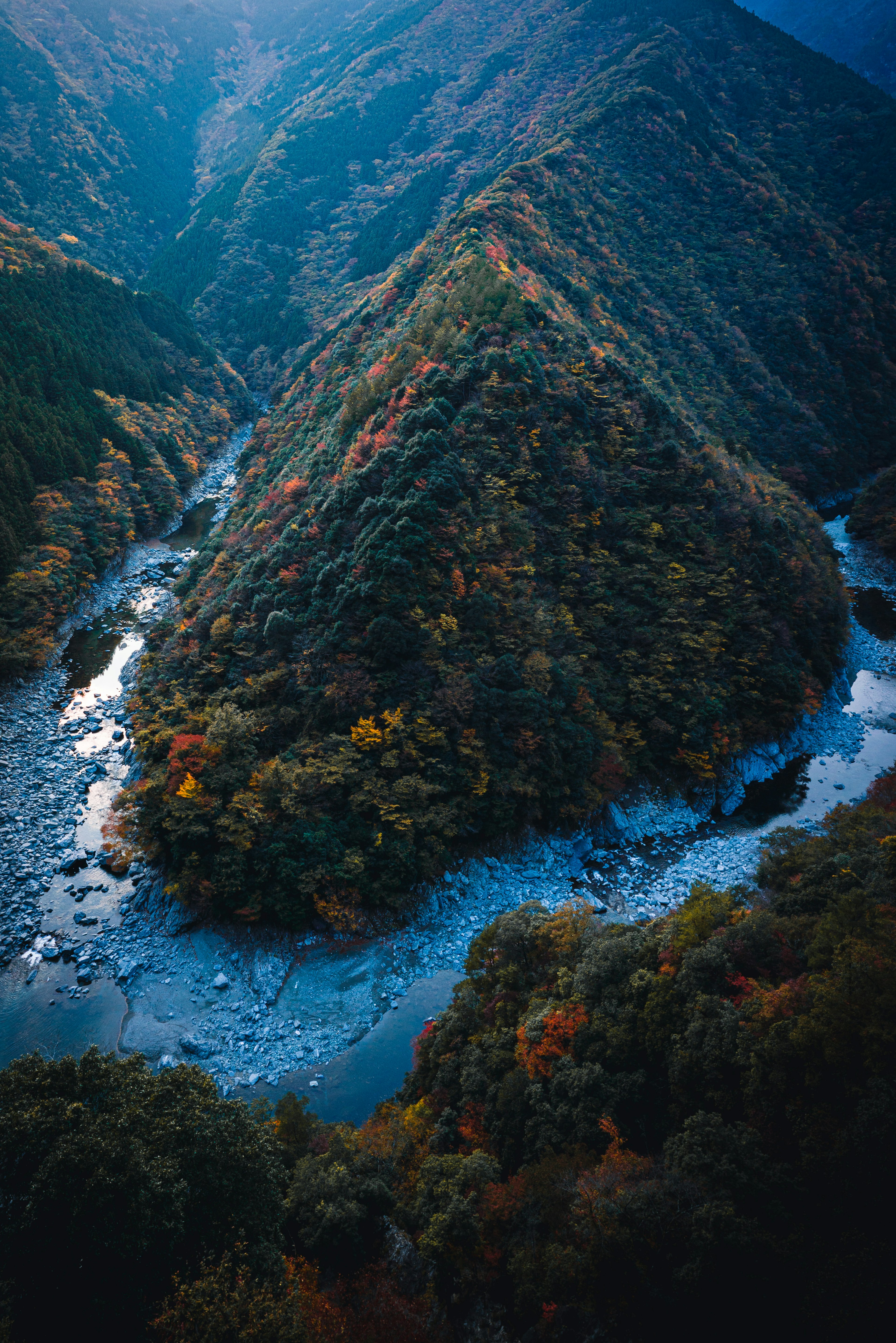 Malersicher Blick auf einen gewundenen Fluss, umgeben von buntem Herbstlaub und Bergen