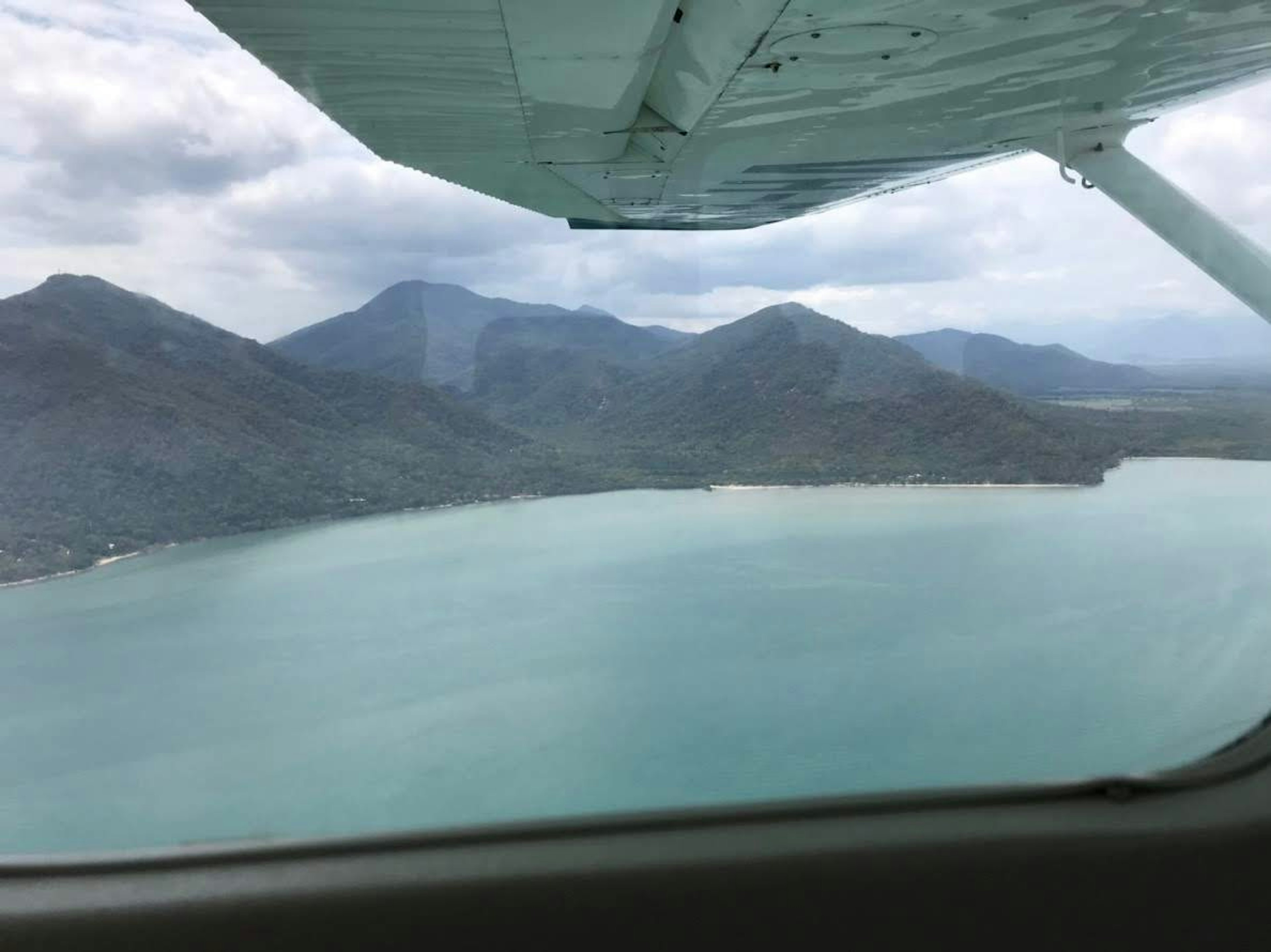 Pemandangan udara laut dan pegunungan dari jendela pesawat