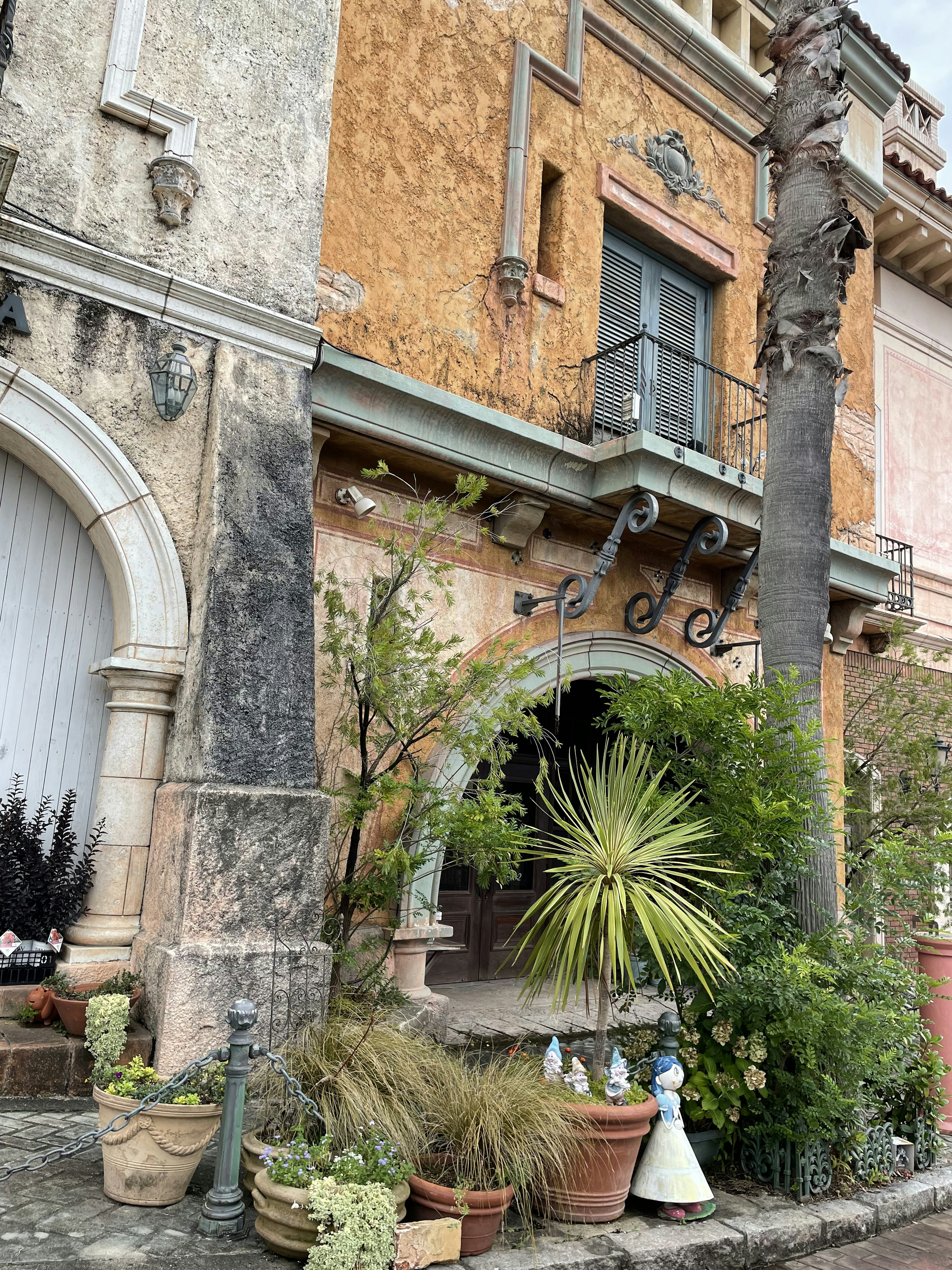 Exterior de un edificio antiguo adornado con hermosas plantas y con paredes desgastadas y una entrada en arco