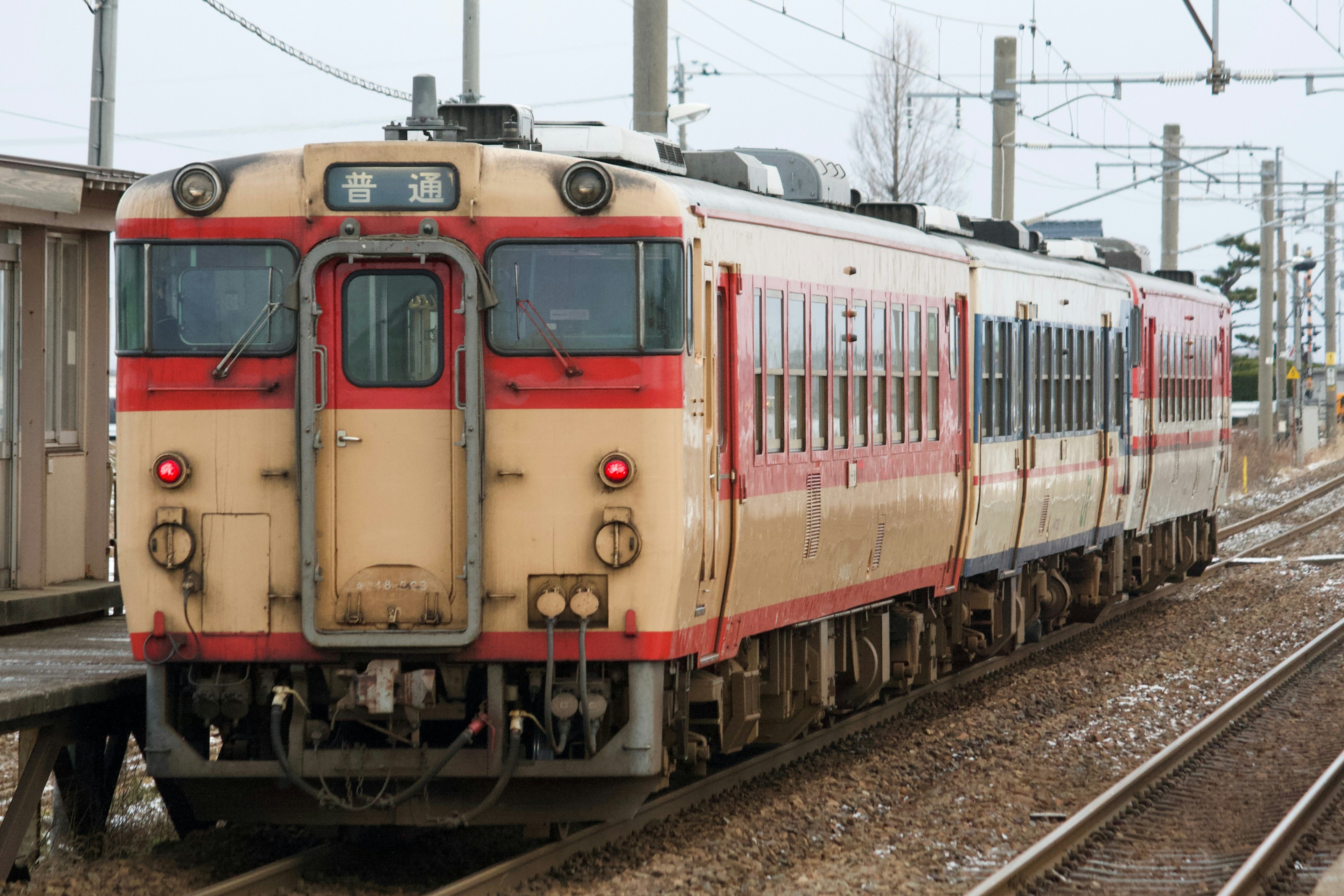 Un treno rosso e crema fermo a una stazione