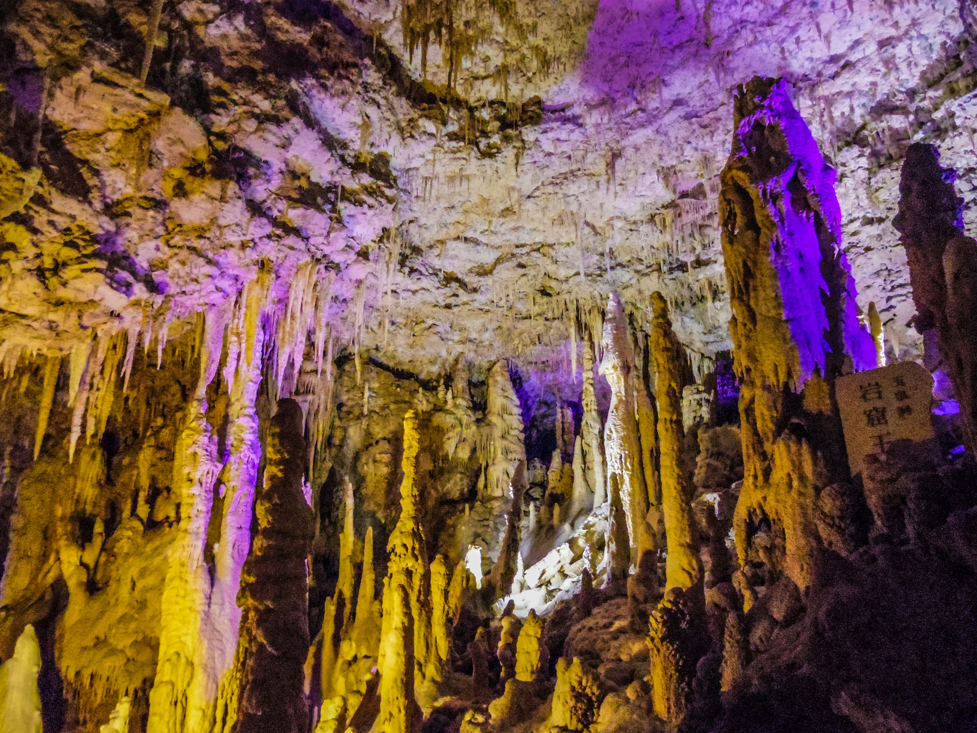 Interno di una grotta con stalagmiti e illuminazione colorata