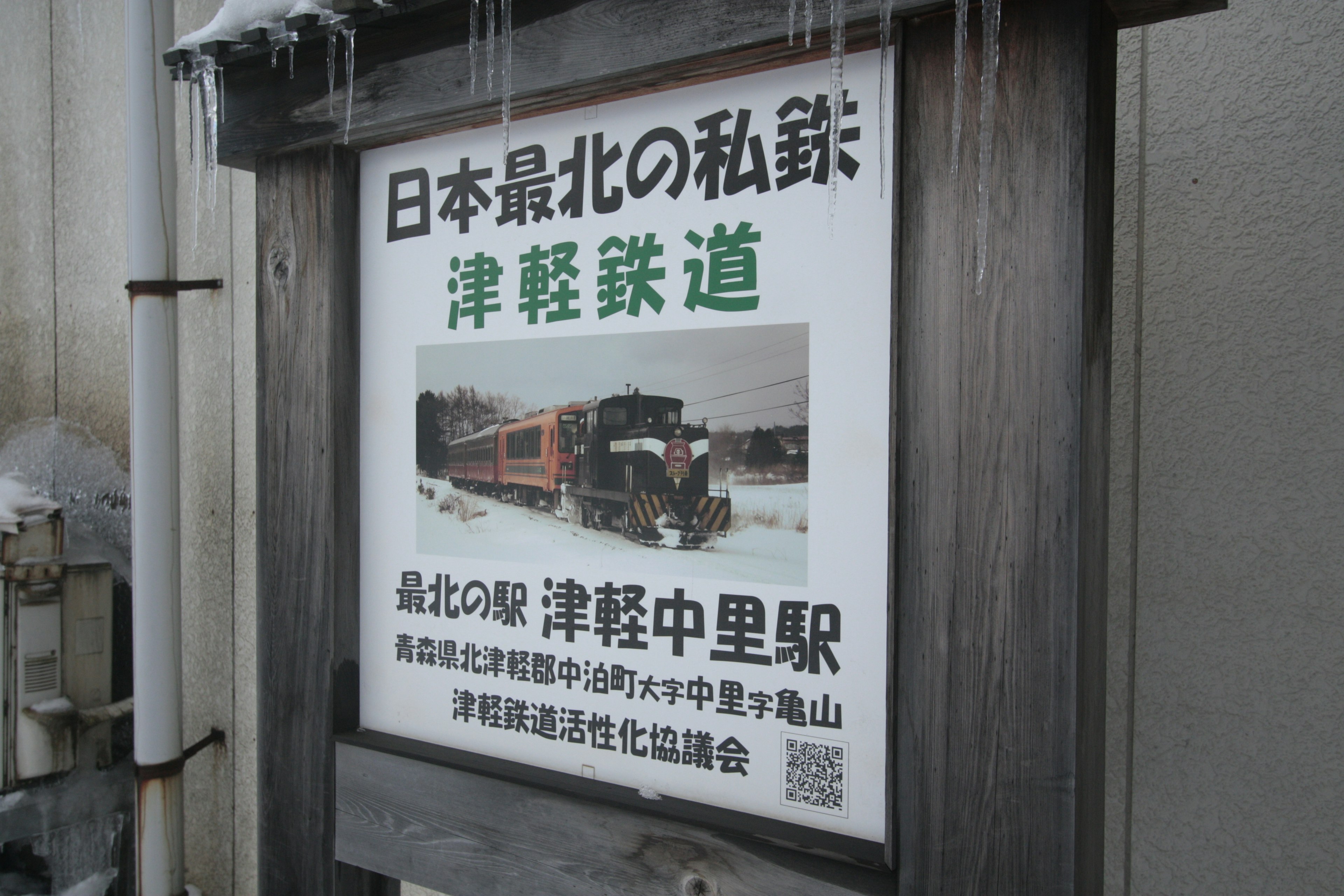 Insegna della stazione della ferrovia Tsugaru con sfondo innevato