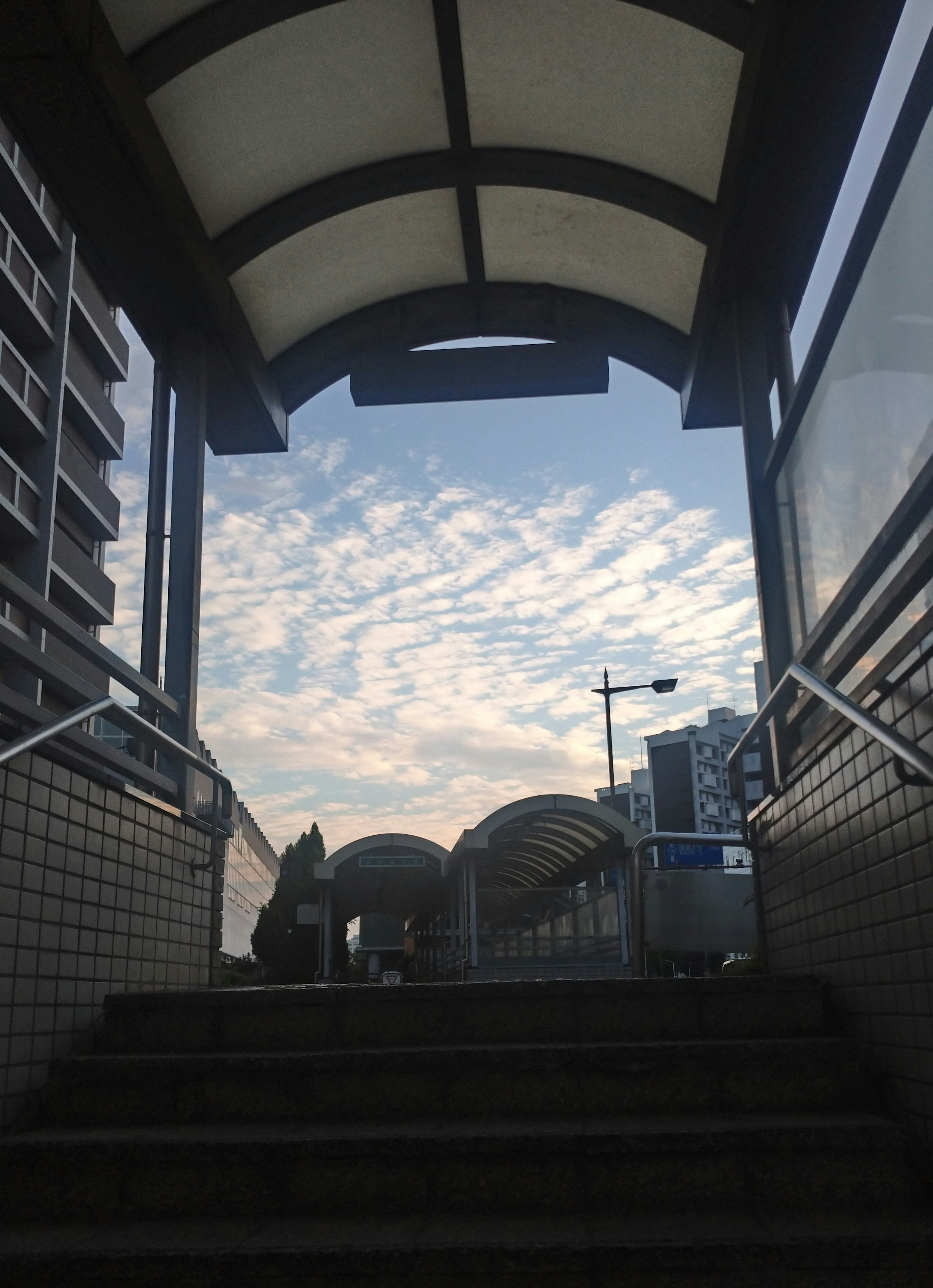 Arco que lleva a un cielo azul con nubes sobre la escalera