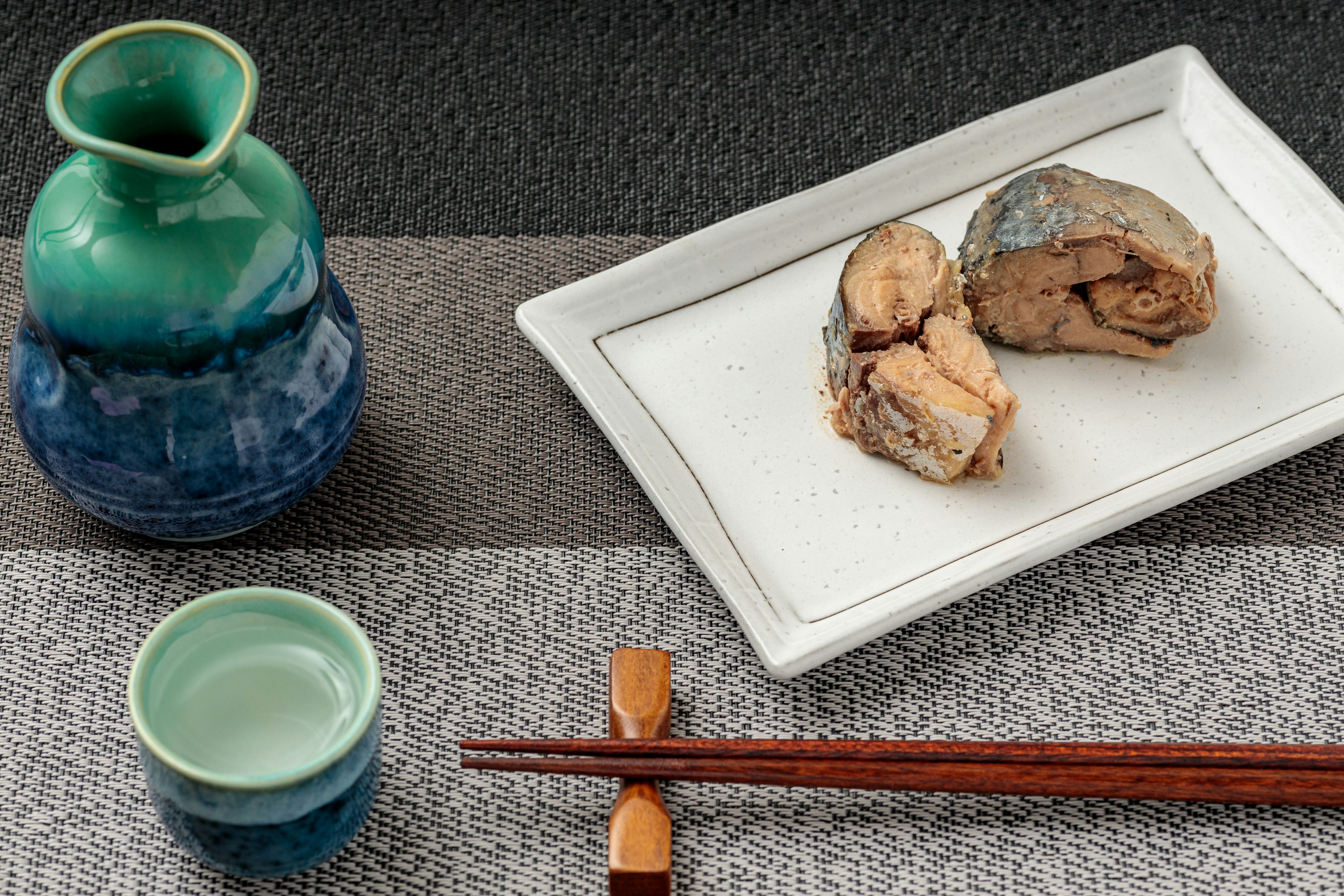 Botella de sake de cerámica y plato con un plato de pescado