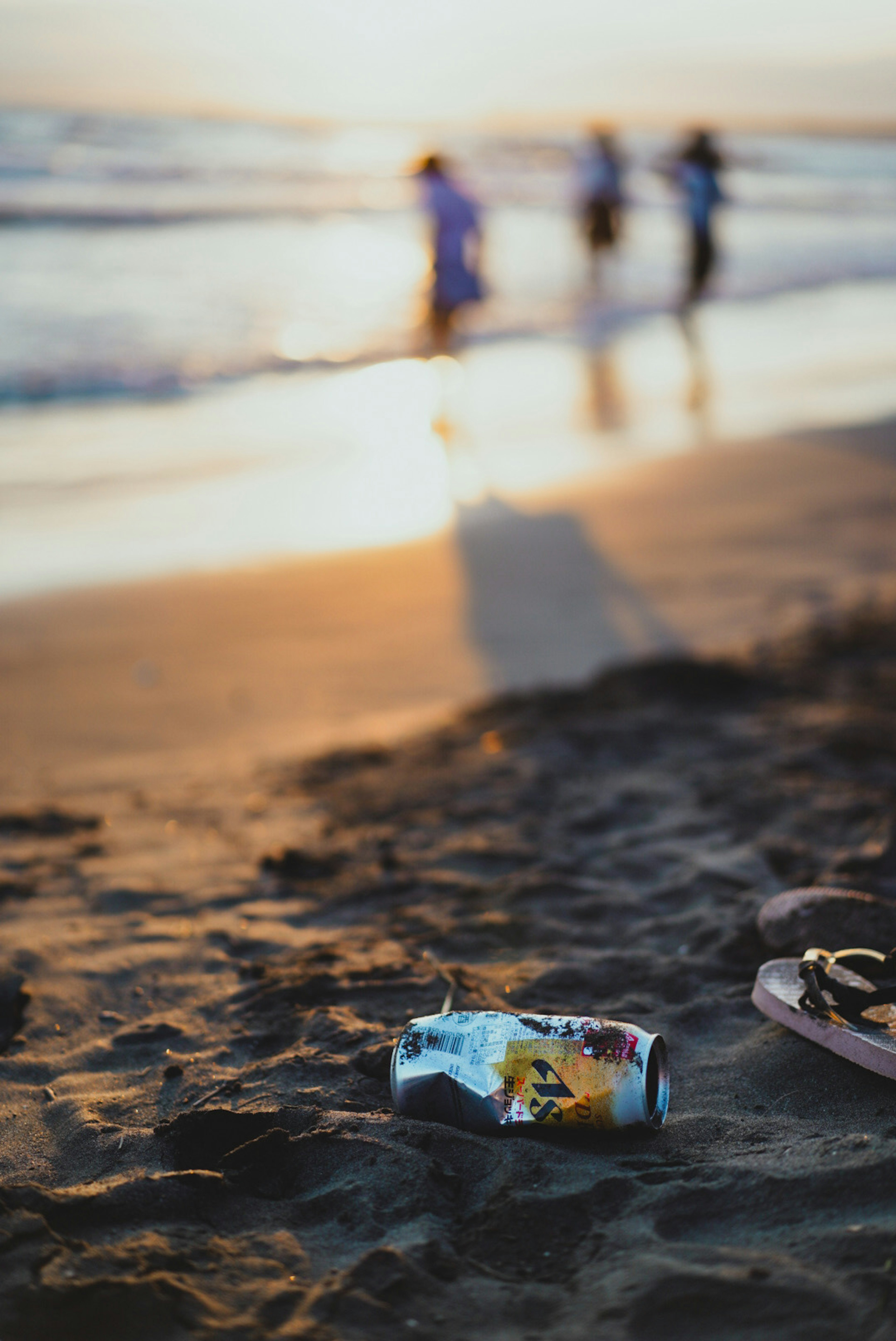 Lata colorida en la playa con siluetas de personas al fondo