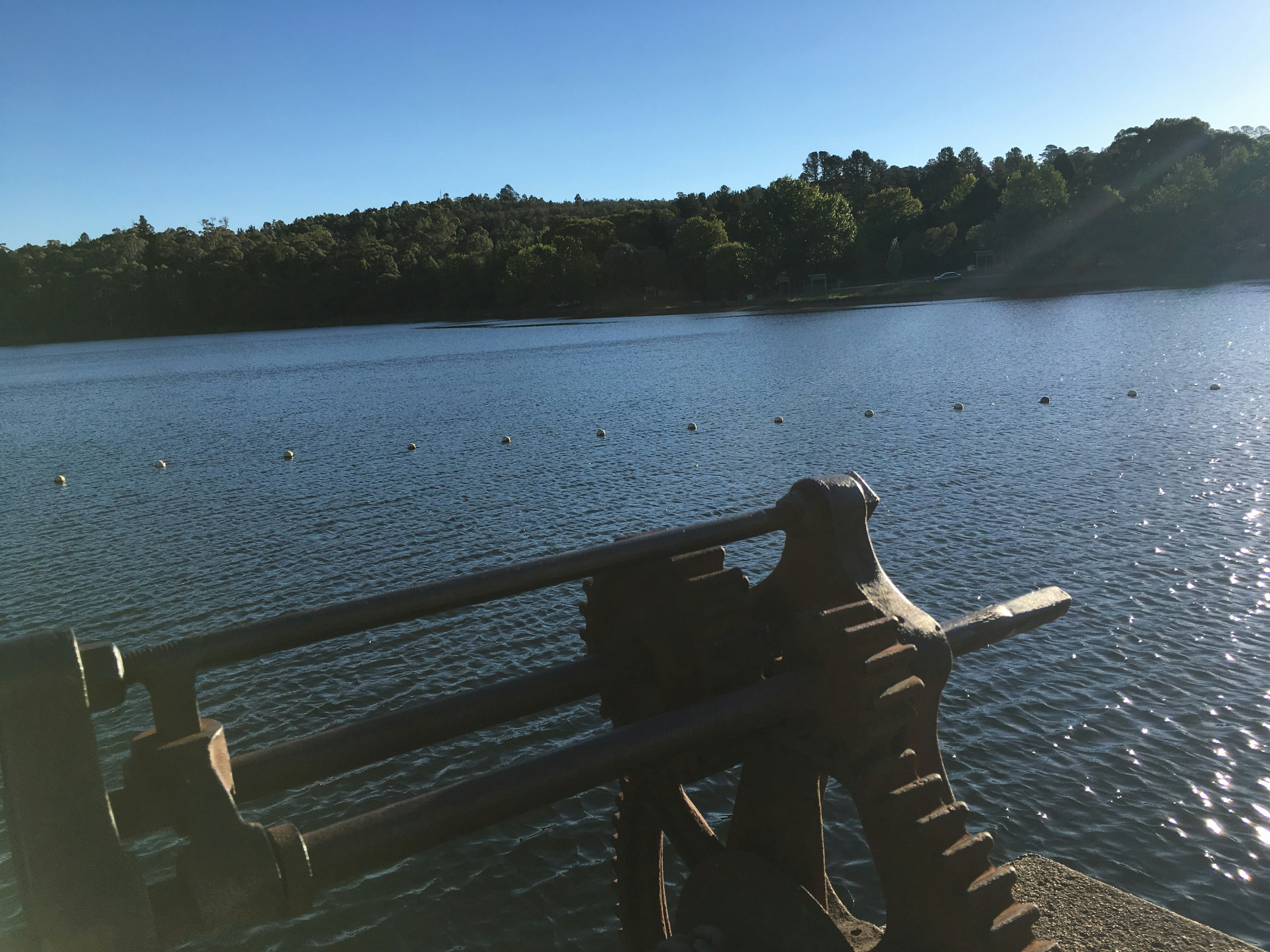 A tranquil lake reflecting the sky with an old mechanical part in the foreground