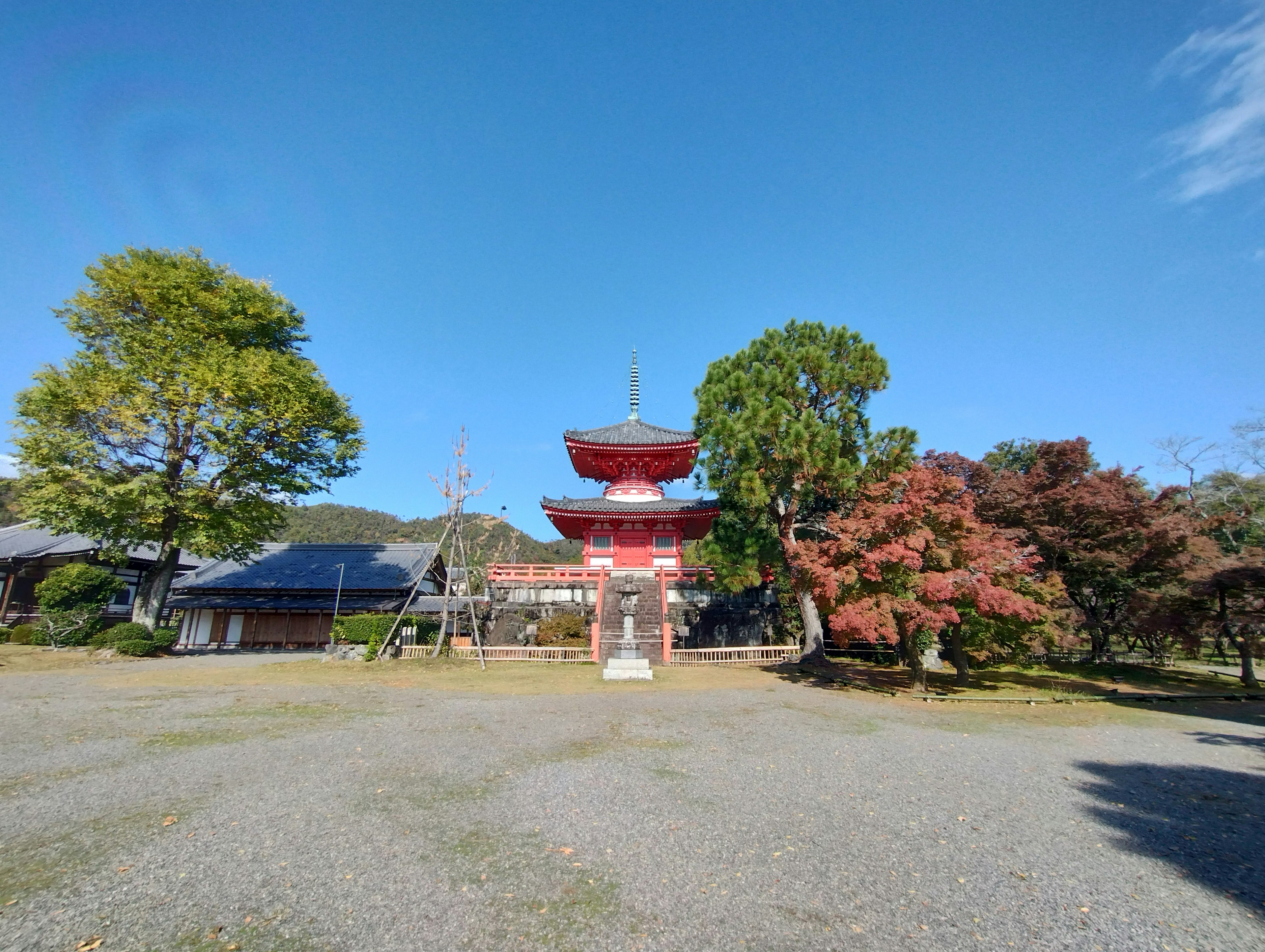 Red five-story pagoda surrounded by green trees under a clear sky